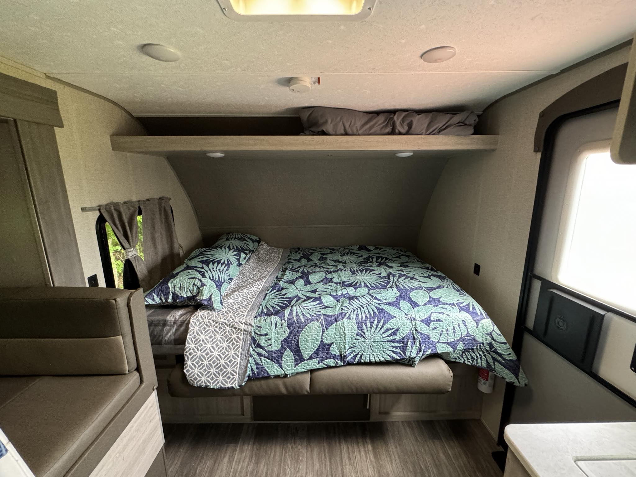 Cozy RV rental interior showing a comfortable bed, overhead storage, and seating area. Ideal for a relaxing trip.. Forest River Aurora Aurora 2022