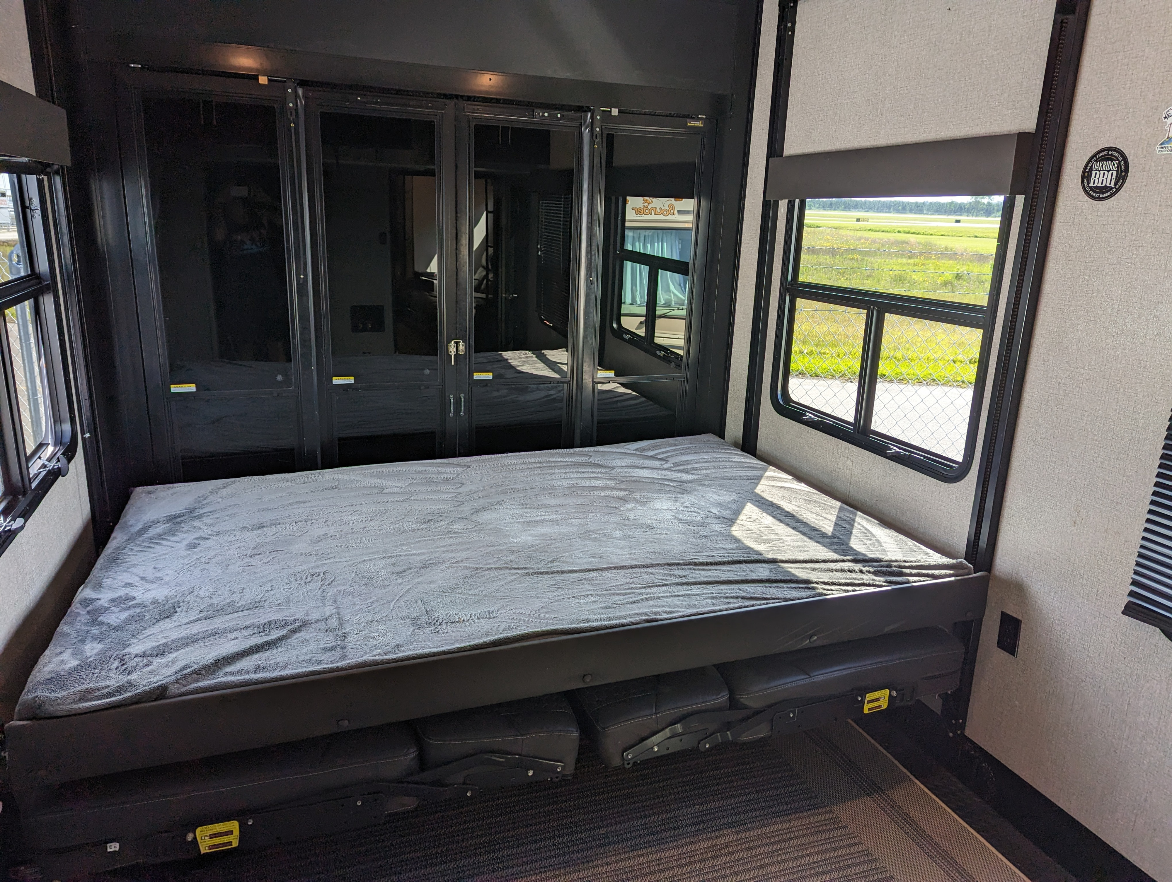 Interior of an RV rental, featuring a convertible bed, garage doors, and windows showcasing outdoor views. Great for camping trips.. Jayco Seismic 2021