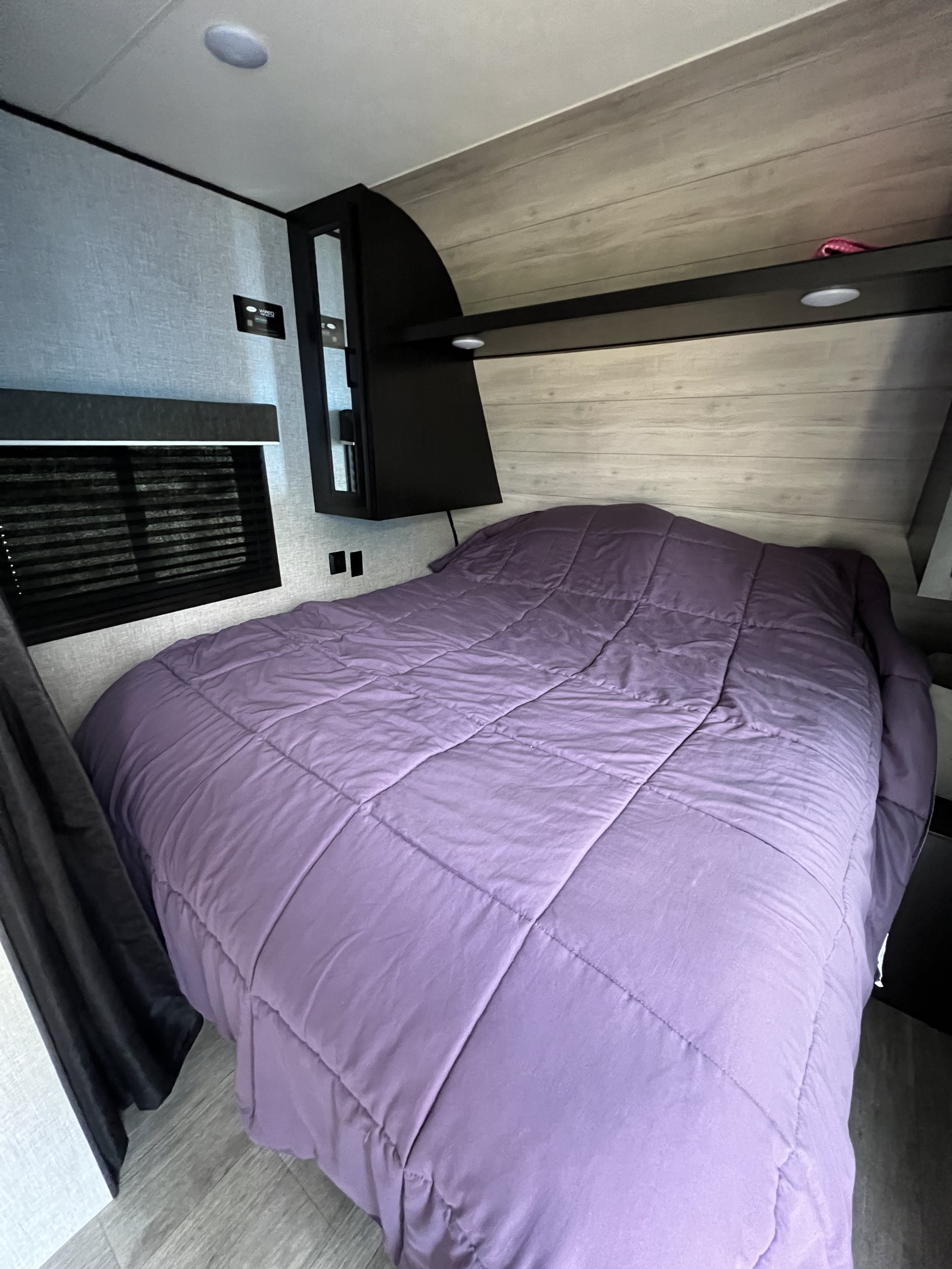 RV rental bedroom featuring a bed with a vibrant purple comforter, window blinds, and modern built-in cabinetry.. Jayco Jay Flight SLX 2022