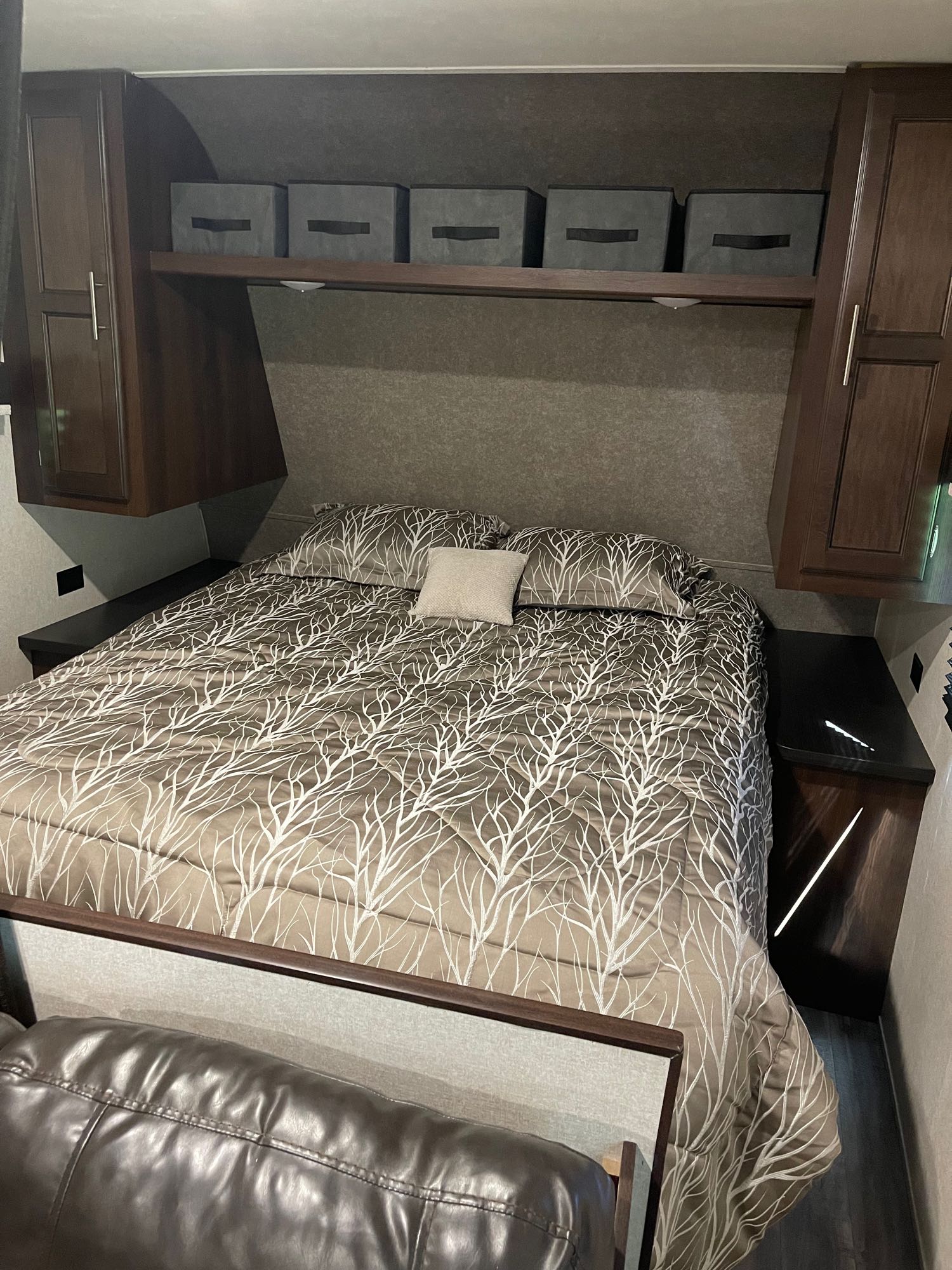Cozy RV rental bedroom interior featuring a bed with a tree-patterned comforter, built-in storage, and nightstands.. Jayco Jay Flight 2019