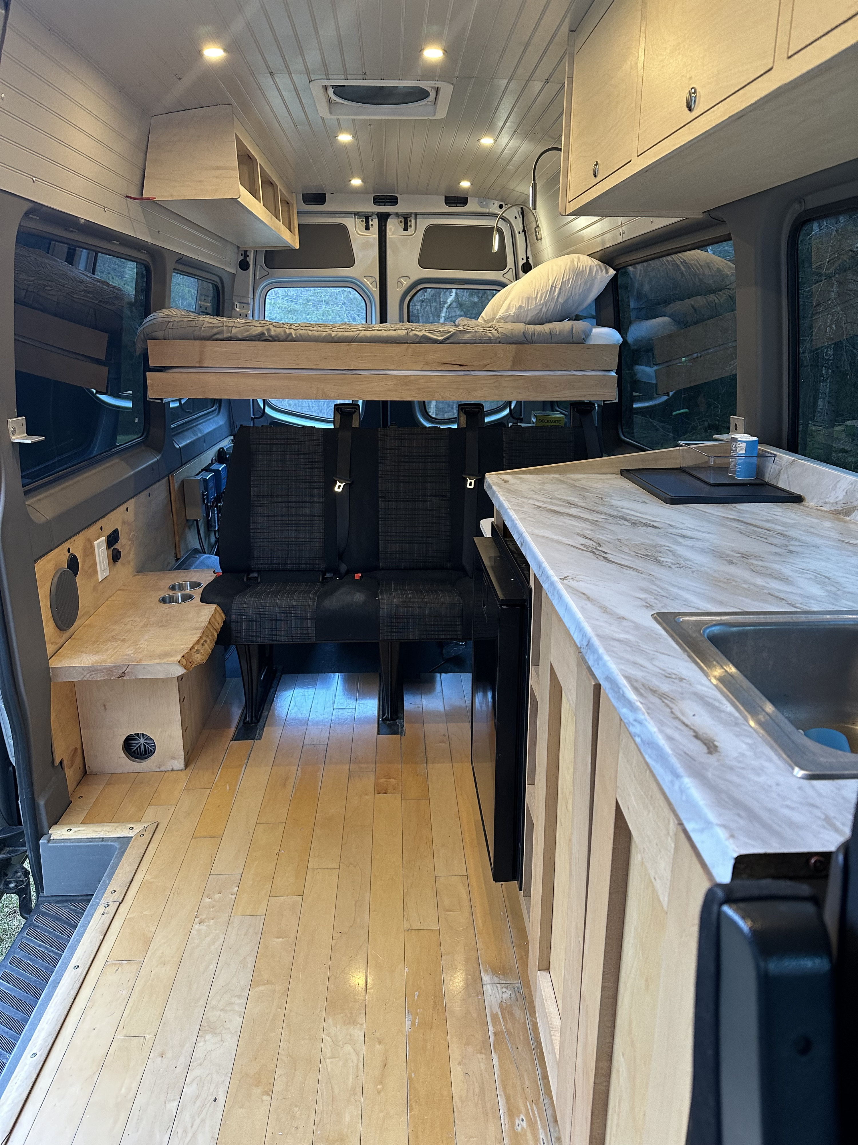 RV rental: custom wood interior featuring elevated bed, kitchen, and rear seating area.. Mercedes-Benz Sprinter 2016