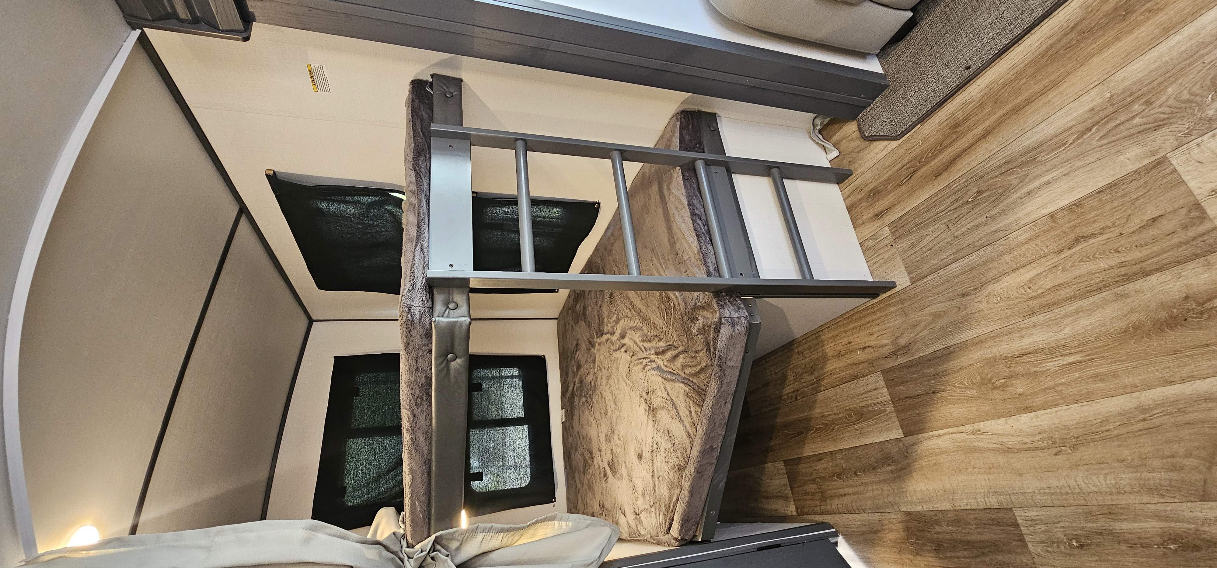 RV rental interior showing bunk beds with ladder, privacy shades on windows, & wood floor. Ideal for camper travel.. Keystone RV Bullet Ultra Lite 2023
