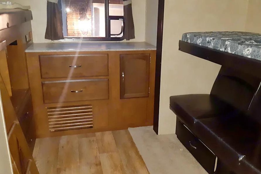 RV rental interior: A compact living space with wooden storage cabinets, a window, and bunk beds with a lower convertible sofa.. Forest River Salem Hemisphere Lite 2016