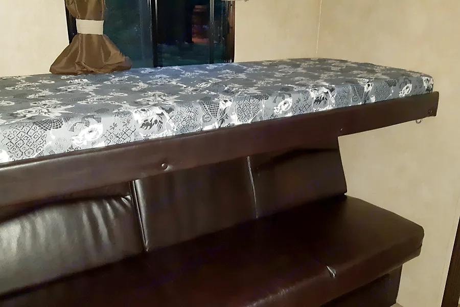 RV rental interior: A patterned mattress on a bunk bed frame sits above a dark leather sofa/dinette, perfect for compact living.. Forest River Salem Hemisphere Lite 2016