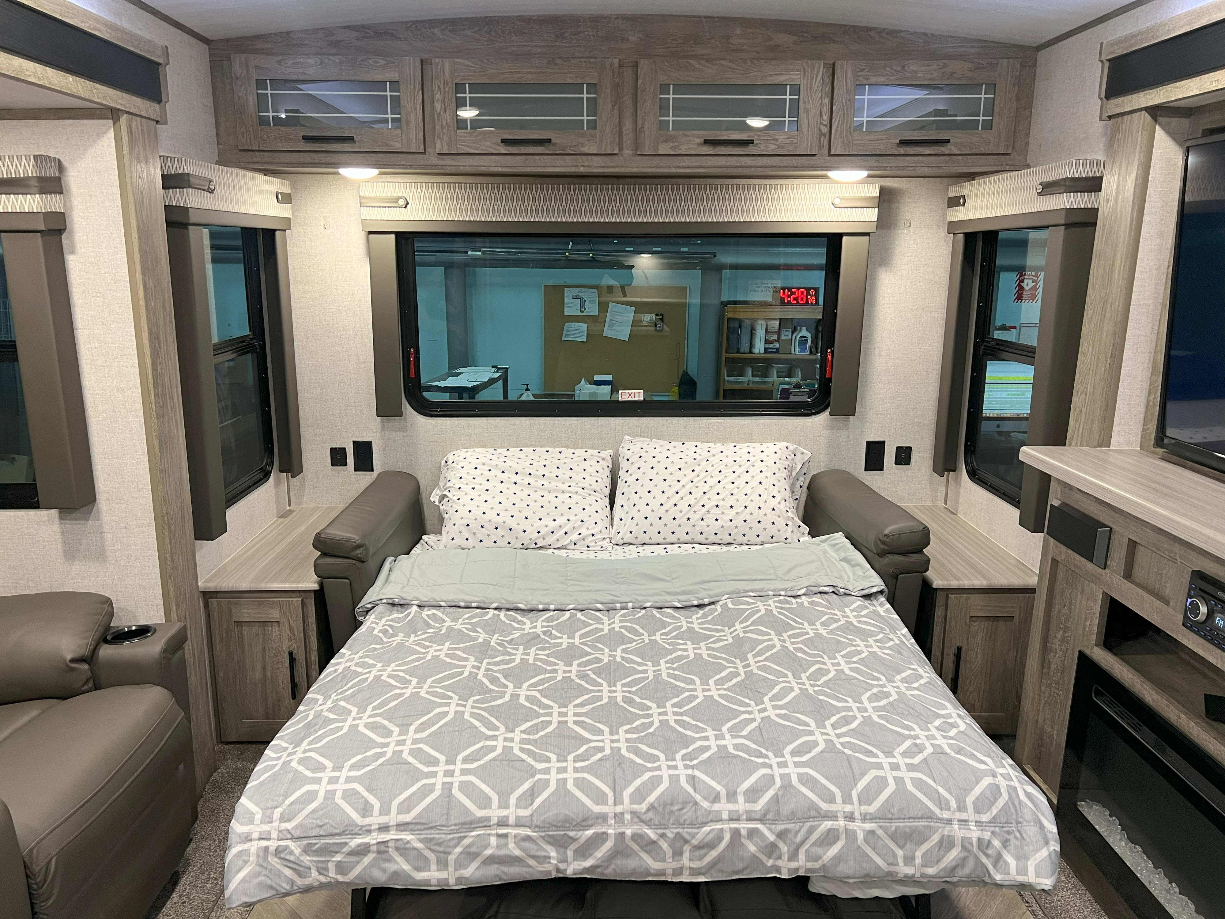 Comfortable RV rental living space featuring a pull-out bed, wooden cabinets, and large windows for a cozy stay.. Forest River Wildwood Heritage Glen 2021