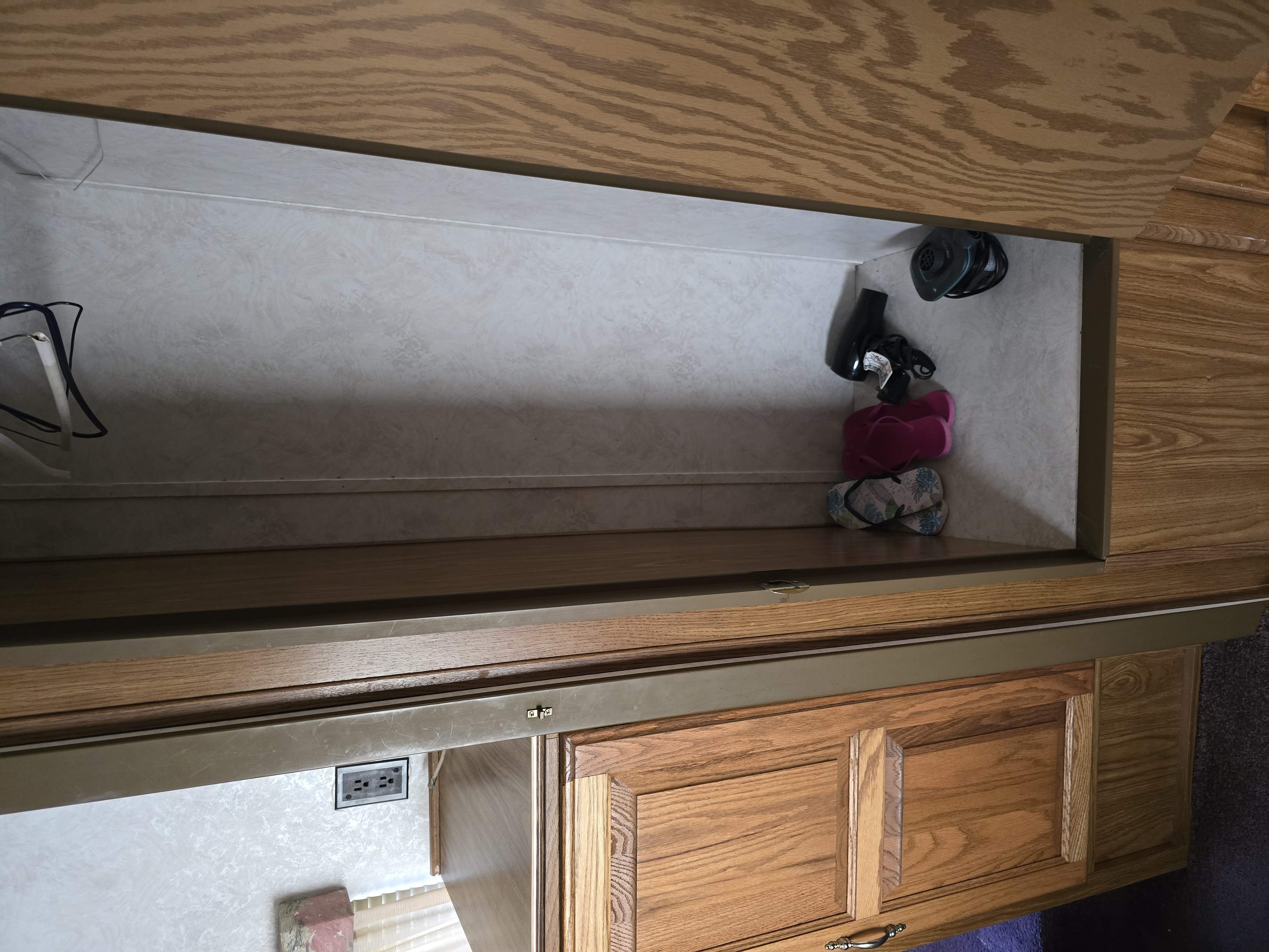 RV rental overhead storage: a neat cubby with a hairdryer, flip-flops, and cables. Ready for your travels!. Dutchmen Royal Classic 1995