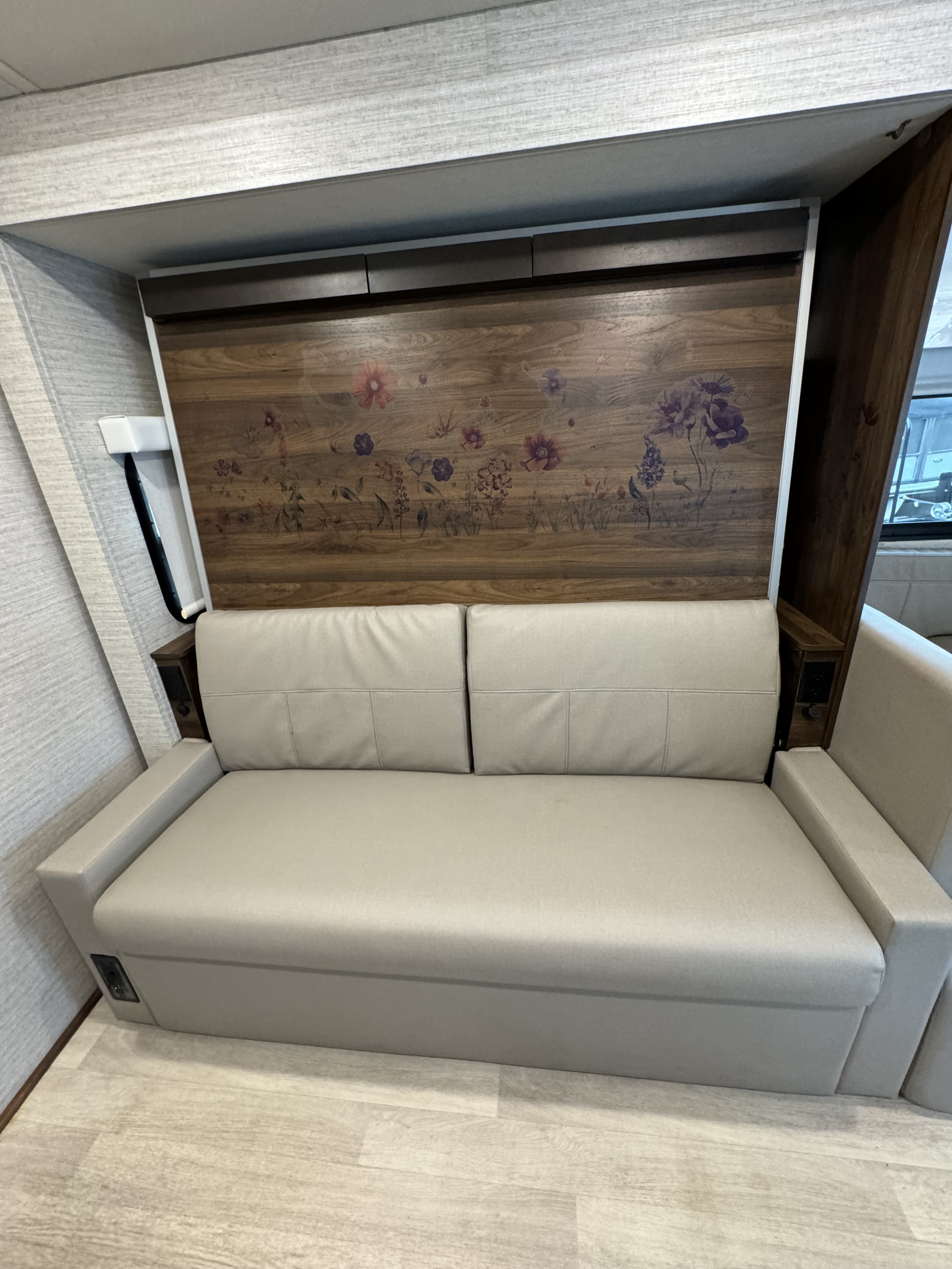Modern light grey rv rental sleeper sofa with integrated outlets and floral wood paneling.. Winnebago View 2022