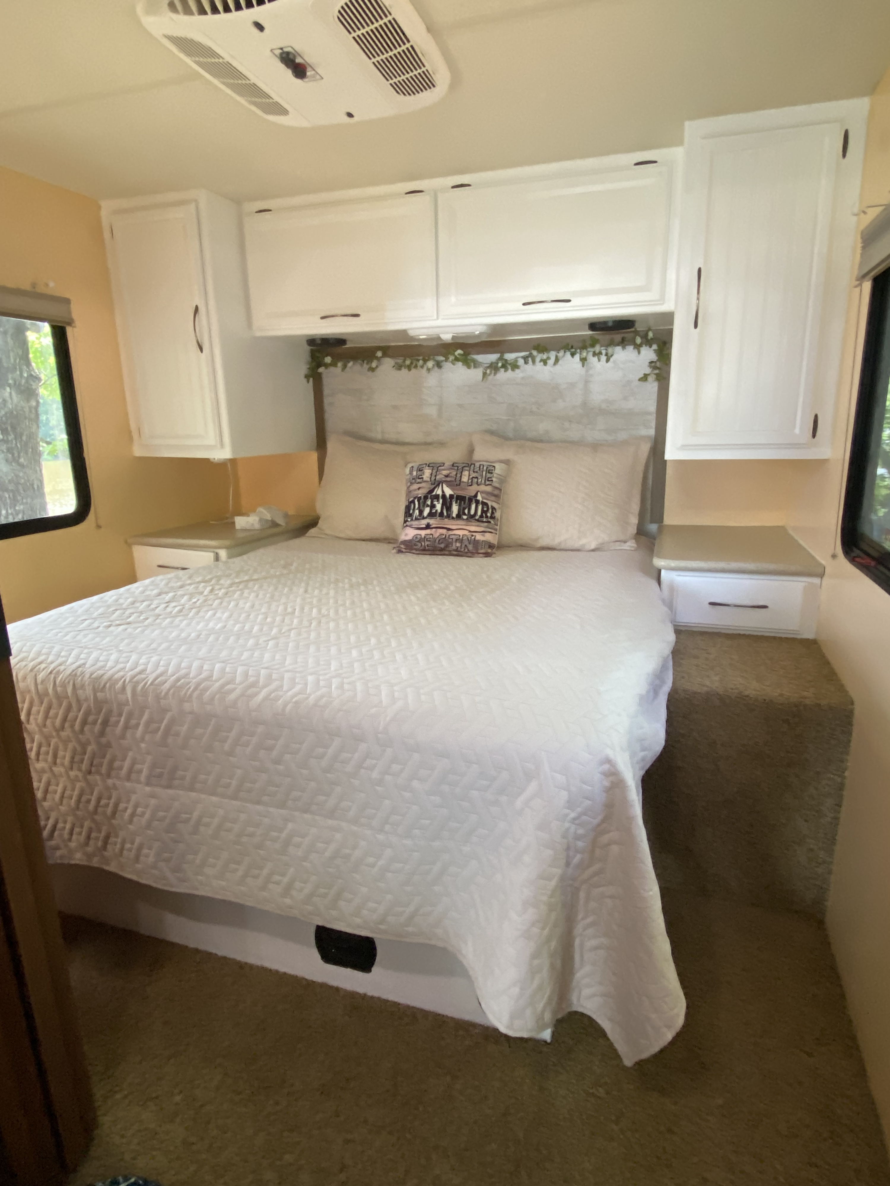 Cozy RV rental bedroom with a large bed, white overhead cabinets, nightstands, and a decorative pillow.. A.C.E. A.C.E. Motorhome 2014