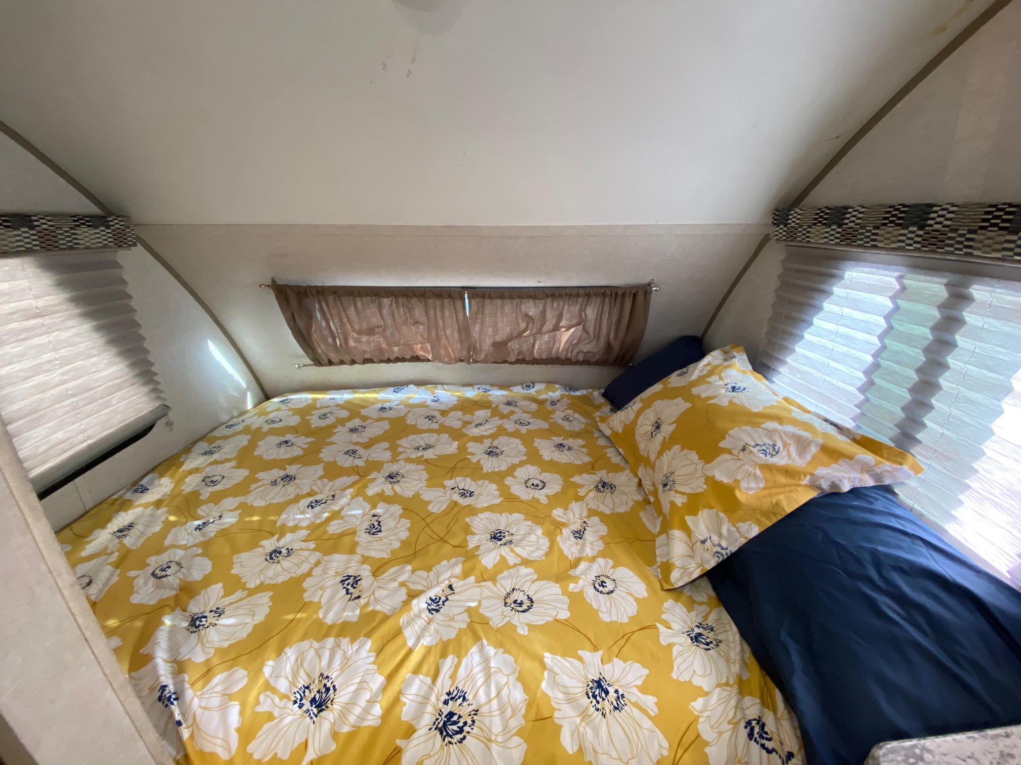 Cozy rv rental bedroom: a vibrant yellow floral duvet covers the bed, accented by a matching pillowcase.. R-Pod Hood River Edition 2017