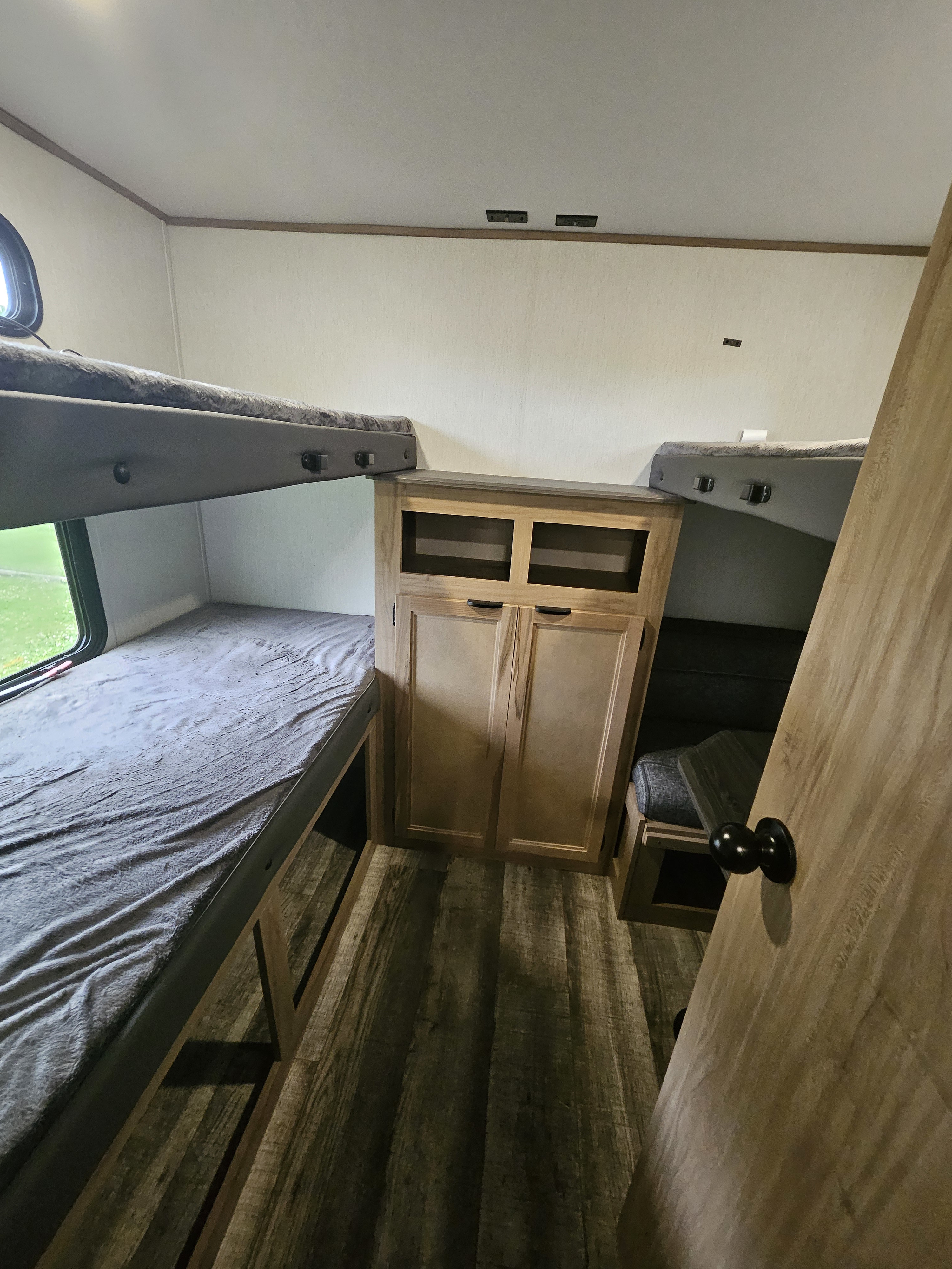 RV rental interior featuring bunk beds, a central storage cabinet, and wood-look flooring. Perfect camper setup.. Forest River Other 2024