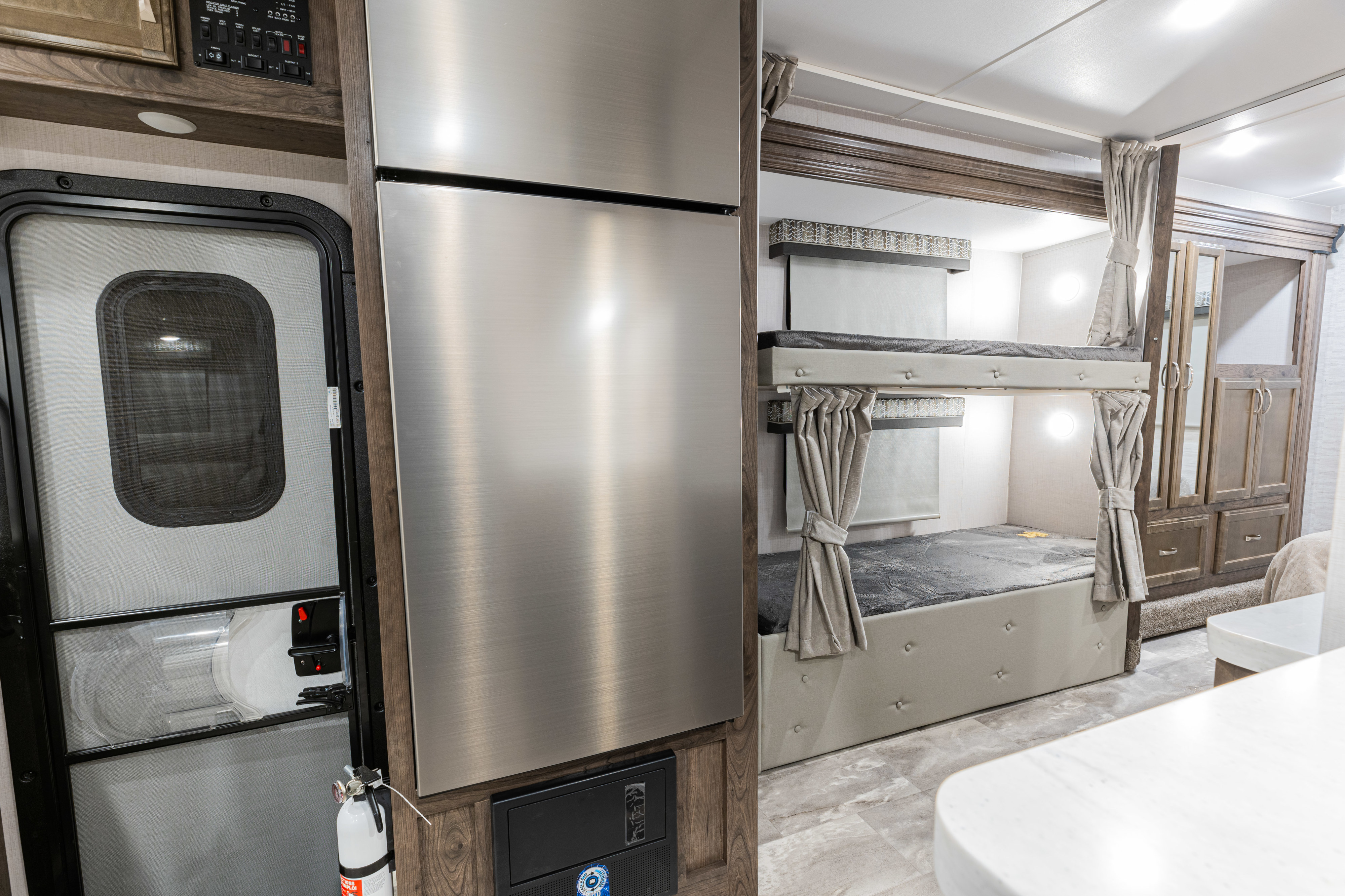 Inside this RV rental, see comfy bunk beds, a stainless steel refrigerator, and an entry door with a fire extinguisher.. Gulf Stream Yellowstone 2023
