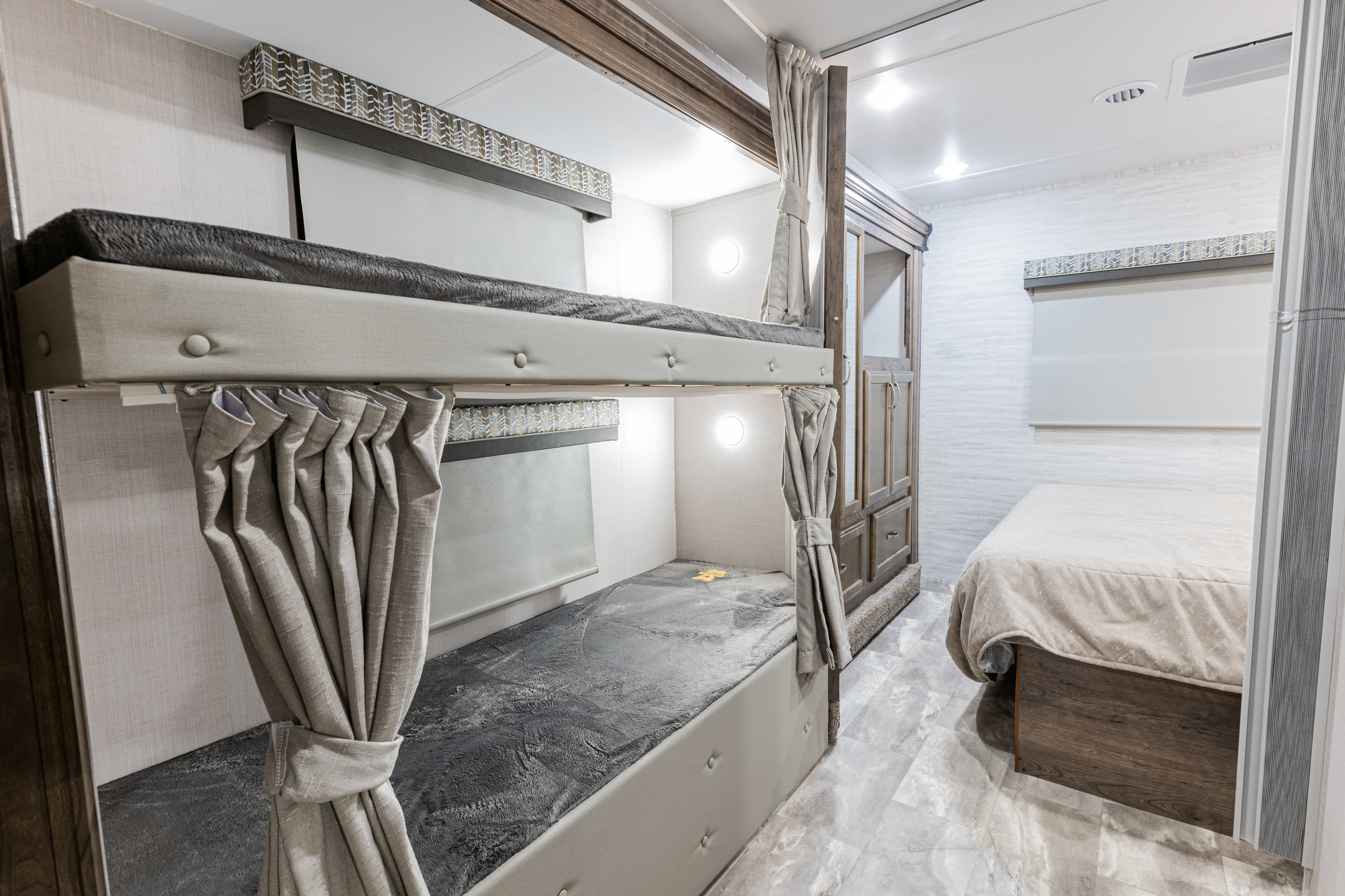 Modern RV rental bedroom with bunk beds, privacy curtains, and a comfortable main bed. Ideal for family adventures.. Gulf Stream Yellowstone 2023