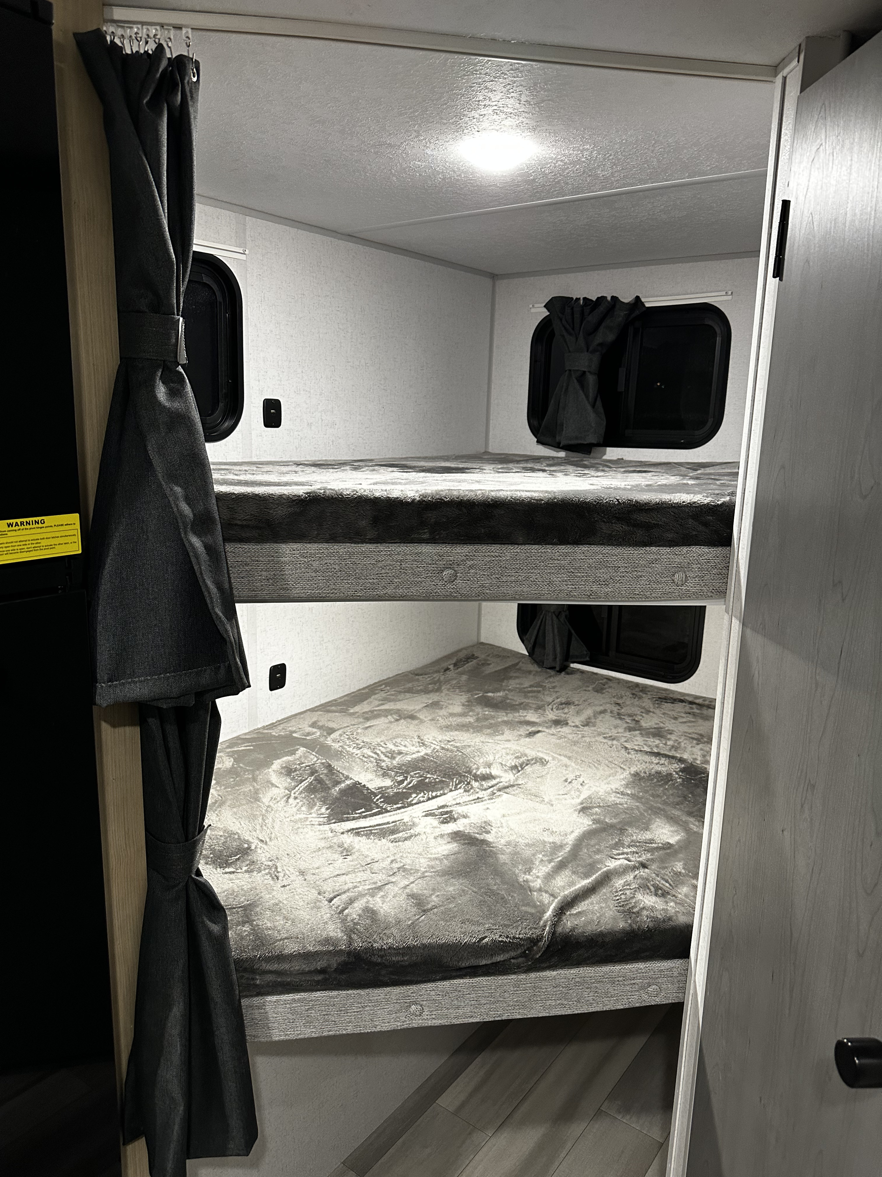 Cozy RV rental interior with comfortable bunk beds, window curtains, and a USB port, offering a functional sleeping area.. Forest River Salem FSX Platinum 2023