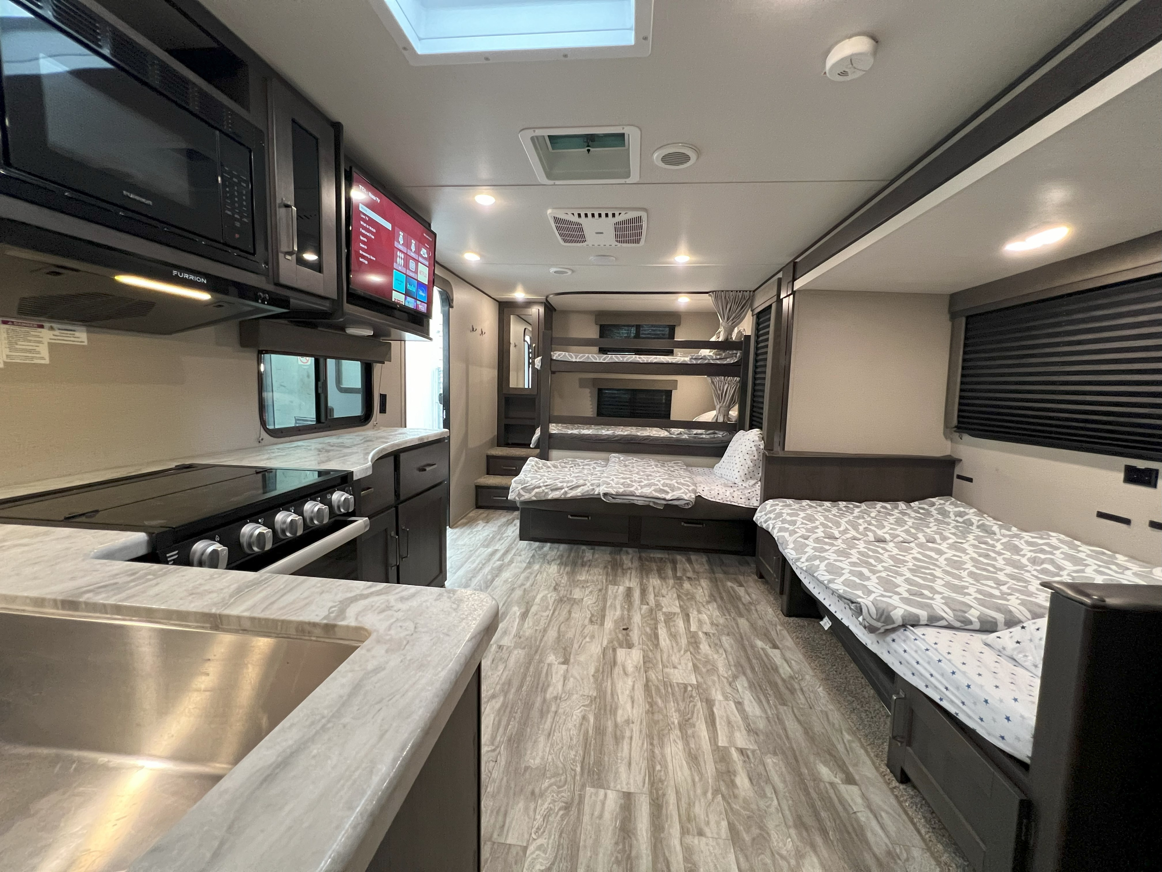 Spacious RV rental interior featuring a modern kitchen, TV, bunk beds, and comfortable sleeping areas.. Grand Design Transcend Xplor 265BH 2021