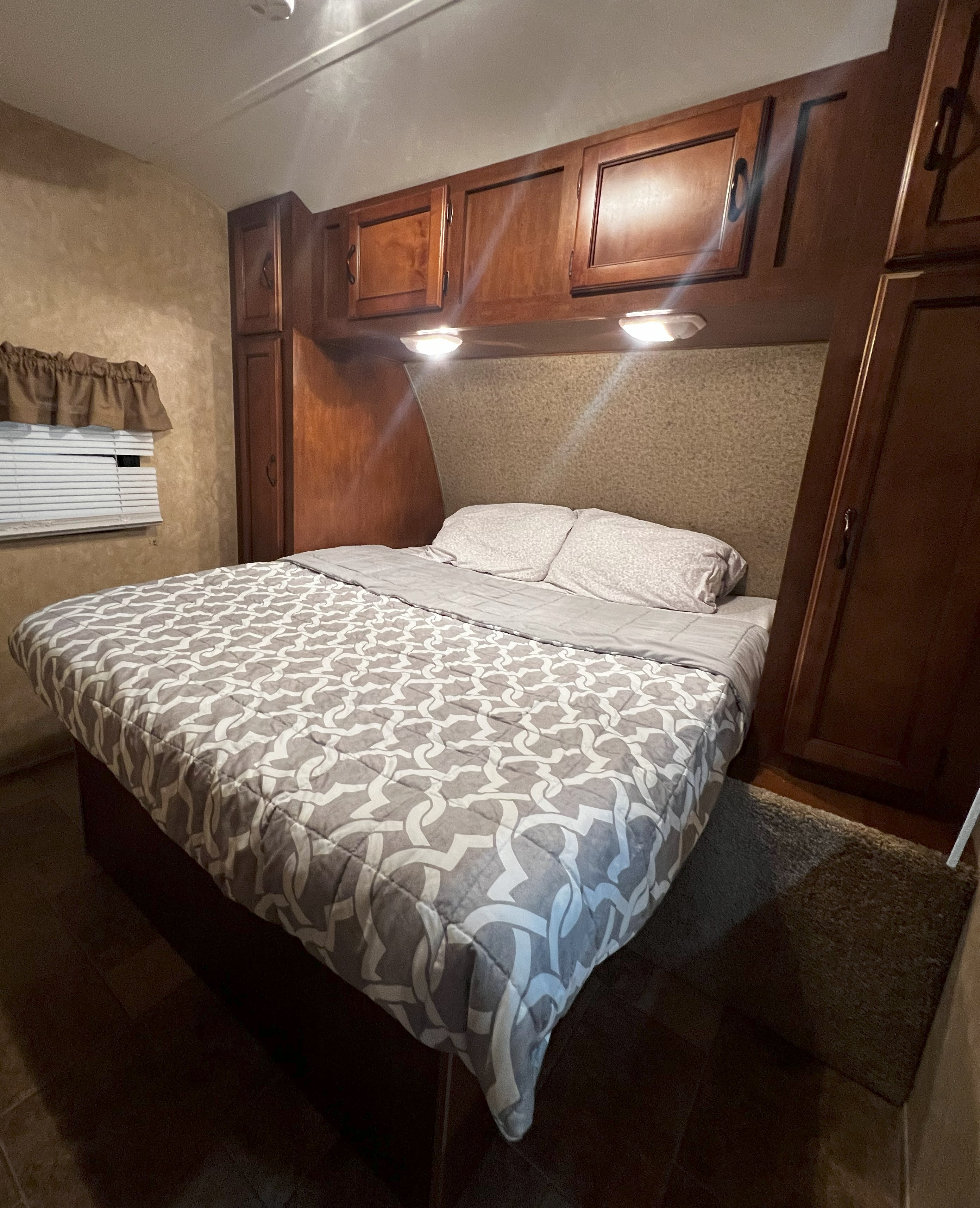 Comfortable RV rental bedroom with a cozy queen bed, overhead storage cabinets, and soft lighting for relaxing travel.. Coachmen Catalina 2012