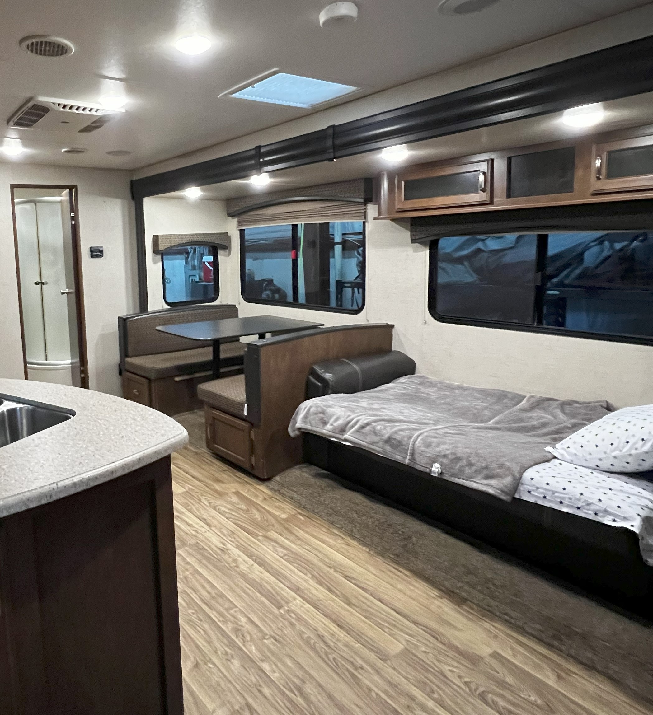 Inside an RV rental: a cozy living space with a dinette, convertible bed, kitchen area, and bathroom access.. Venture Sport Trek 2017