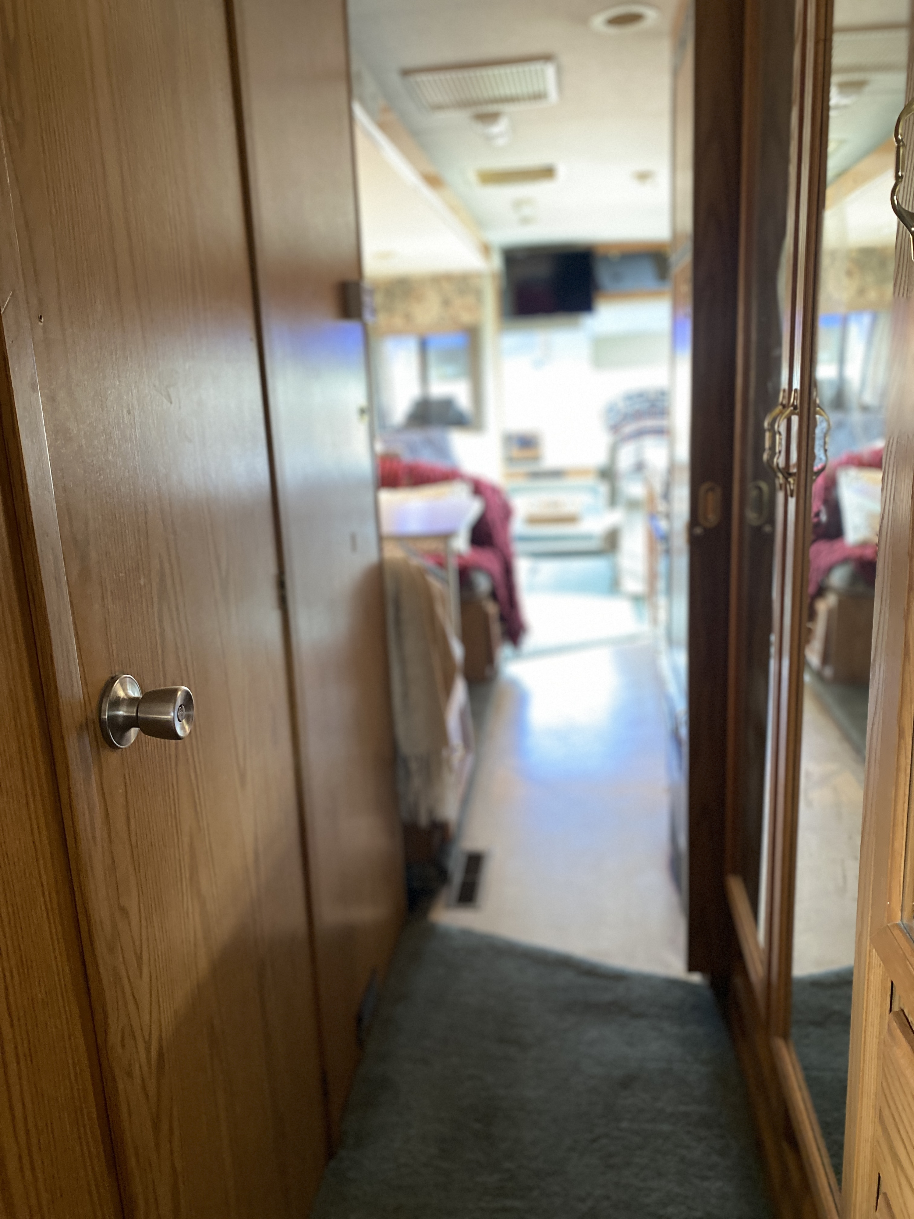 RV rental: a compact interior hallway featuring a wooden door on the left and a mirrored closet on the right, leading to the living area.. Winnebago Adventurer 1996