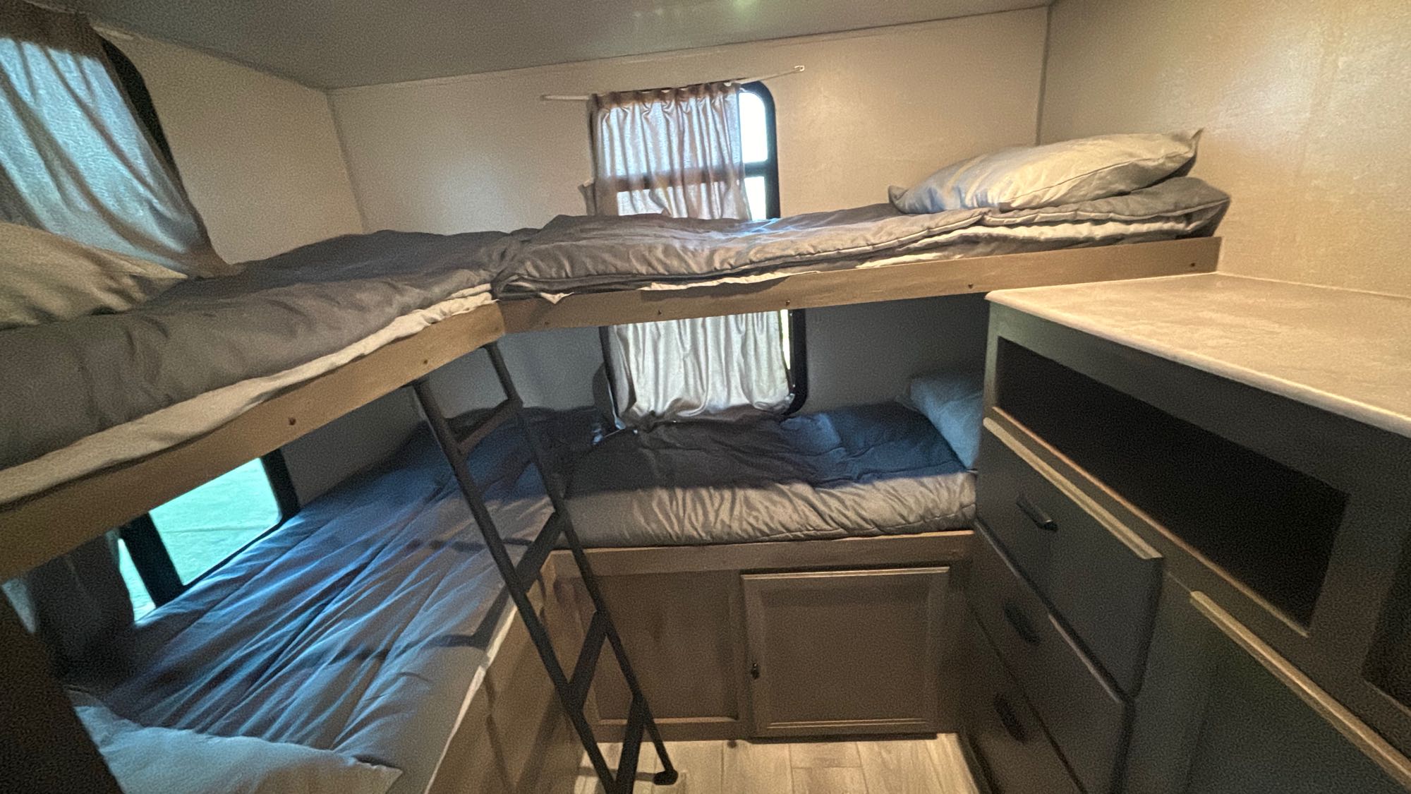 Inside this RV rental, comfortable bunk beds with windows and a ladder provide efficient sleeping arrangements.. Forest River 296 QBLE 2023