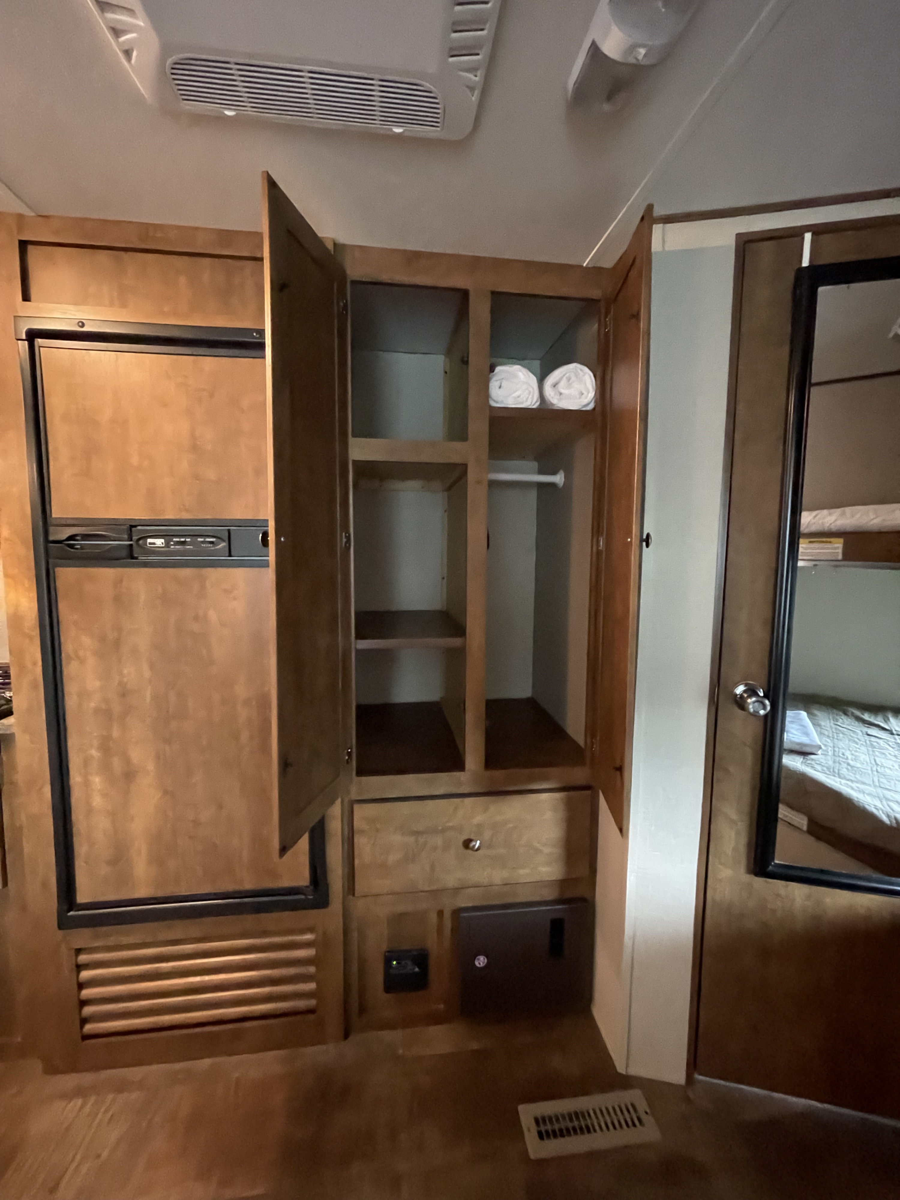 RV rental interior featuring a refrigerator, an open wardrobe with shelves & towels, and a mirrored door.. Z1 ZT272B 2016