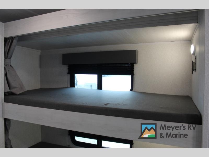 Comfortable bunk beds within an RV rental interior, featuring a window with blinds and integrated lighting.. EAST TO WEST ENTRADA 3100FBF 2024
