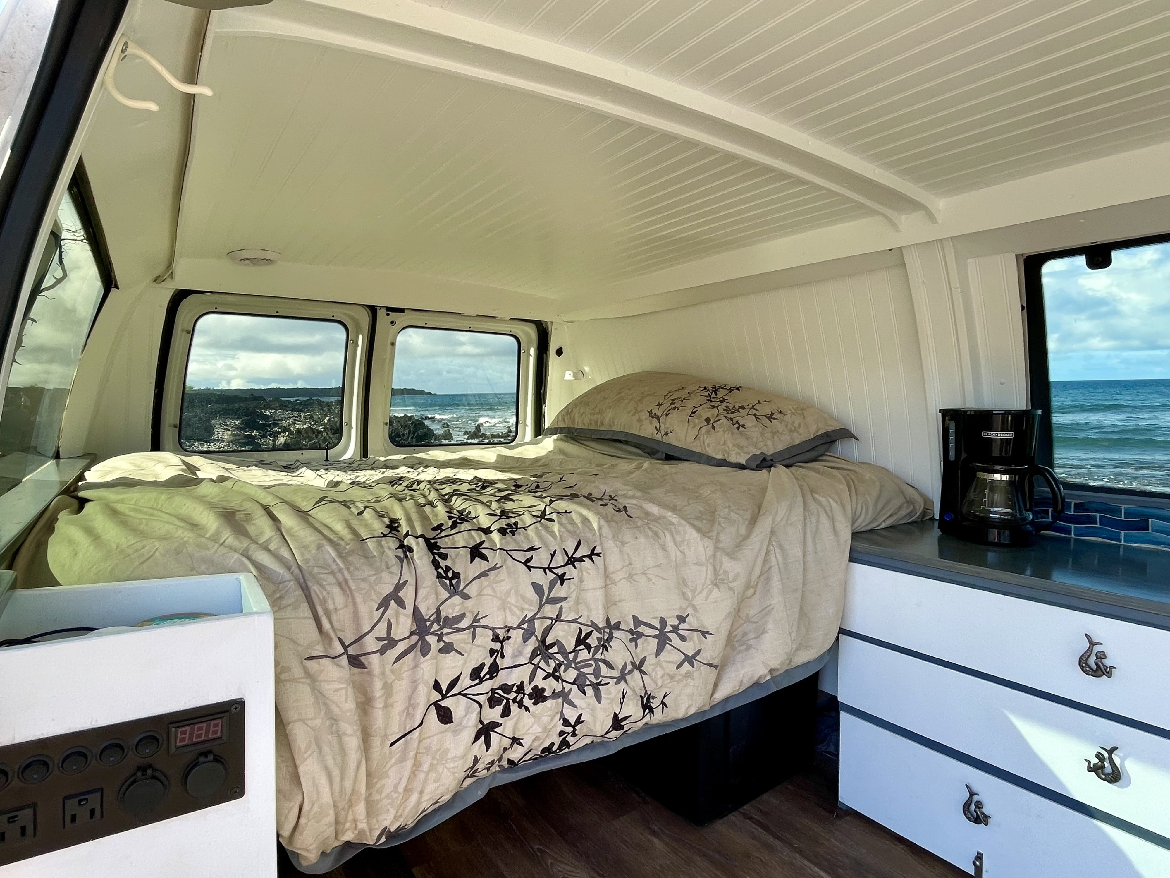 RV rental camper van interior: Features a cozy bed with ocean views, coffee maker, and power panel for your comfort.. Ford Econoline 150 2007