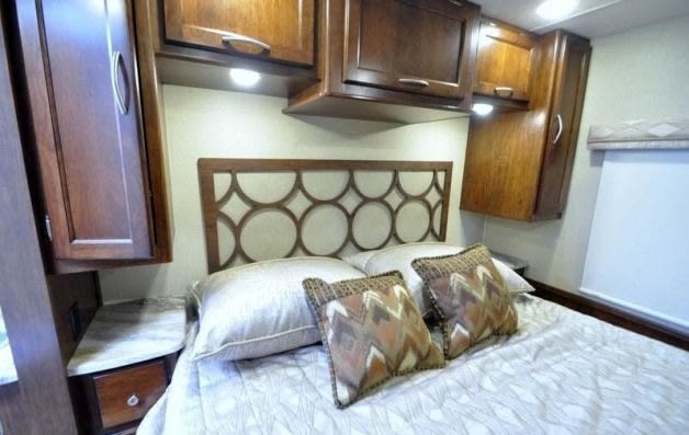 Spacious RV rental bedroom with a modern headboard, ample overhead storage, and cozy lighting.. Forest River Coachmen Pursuit 2023