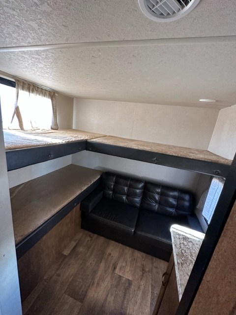 RV rental interior: featuring built-in bunk beds, a black sofa, and wood flooring. Perfect for group travel.. Forest River Salem Cruise Lite 2023