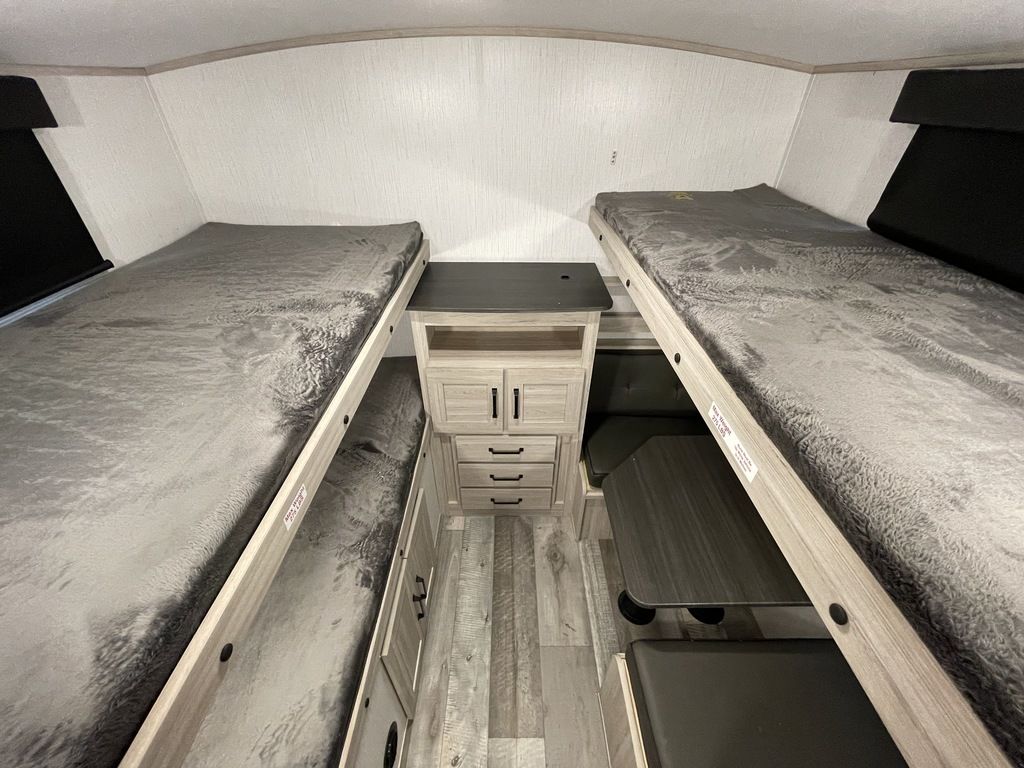 Inside this RV rental, find comfortable bunk beds on each side, a central storage cabinet, and a dinette area for family comfort.. Heartland RVs Sundance Ultra Lite 2022