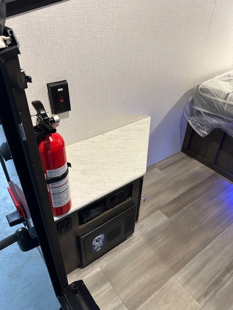 RV rental interior: fire extinguisher on nightstand with outlet & safe, beside bed. Essential safety & storage for your journey.. Viking 9.0TD 2022