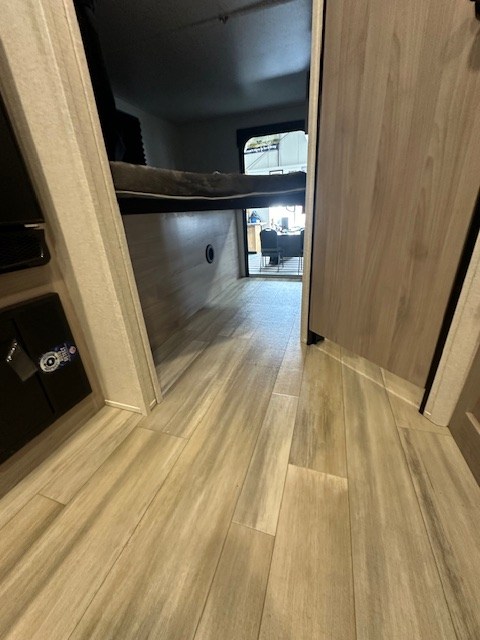 RV rental interior: light wood flooring and raised bed leading to a bright room at the end.. Coachmen 2146BHX 2023