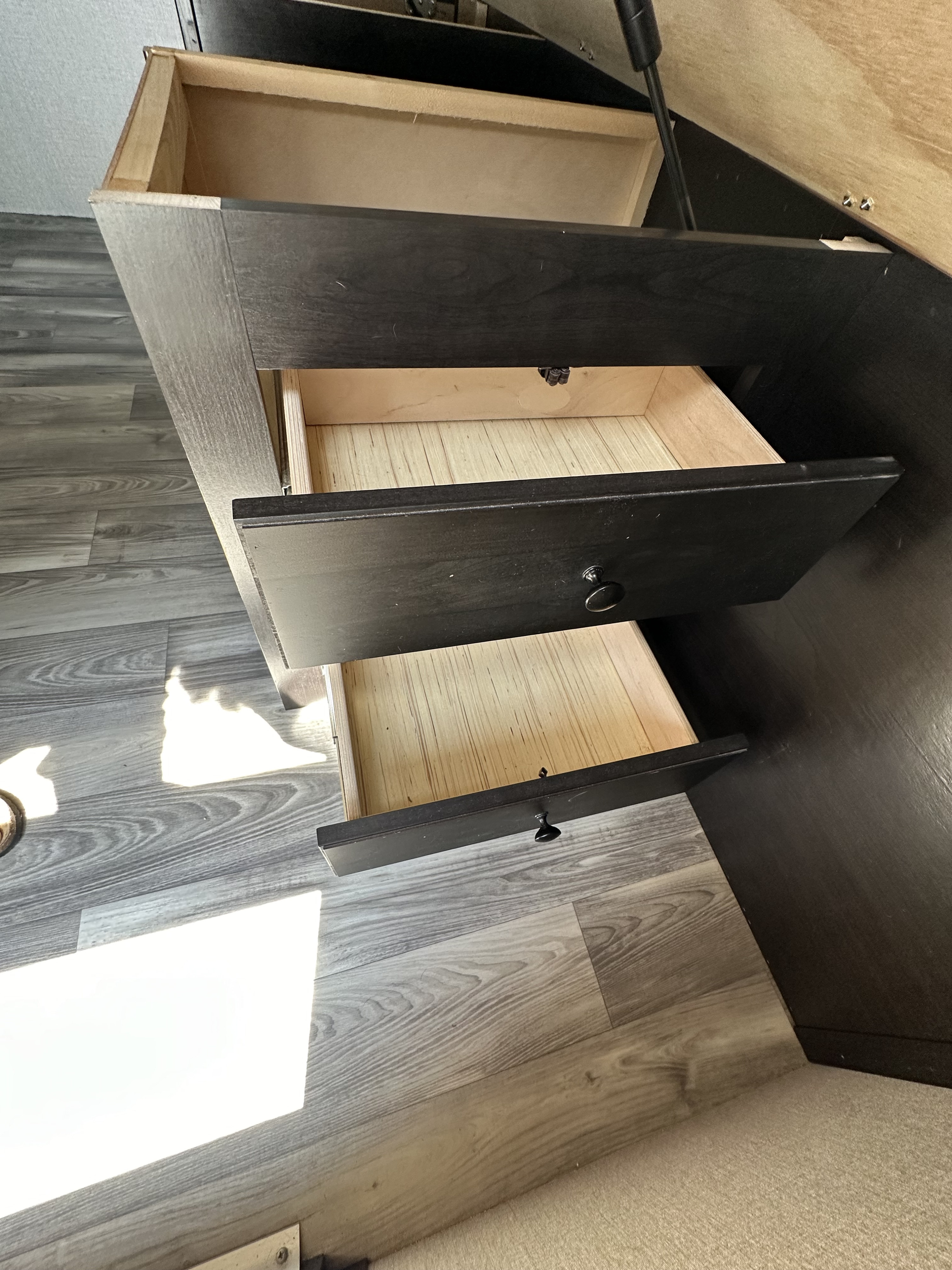View inside an RV rental showing a dark brown storage cabinet with three light-colored, open drawers and wood-patterned flooring.. Highland Ridge RV Open Range 2022