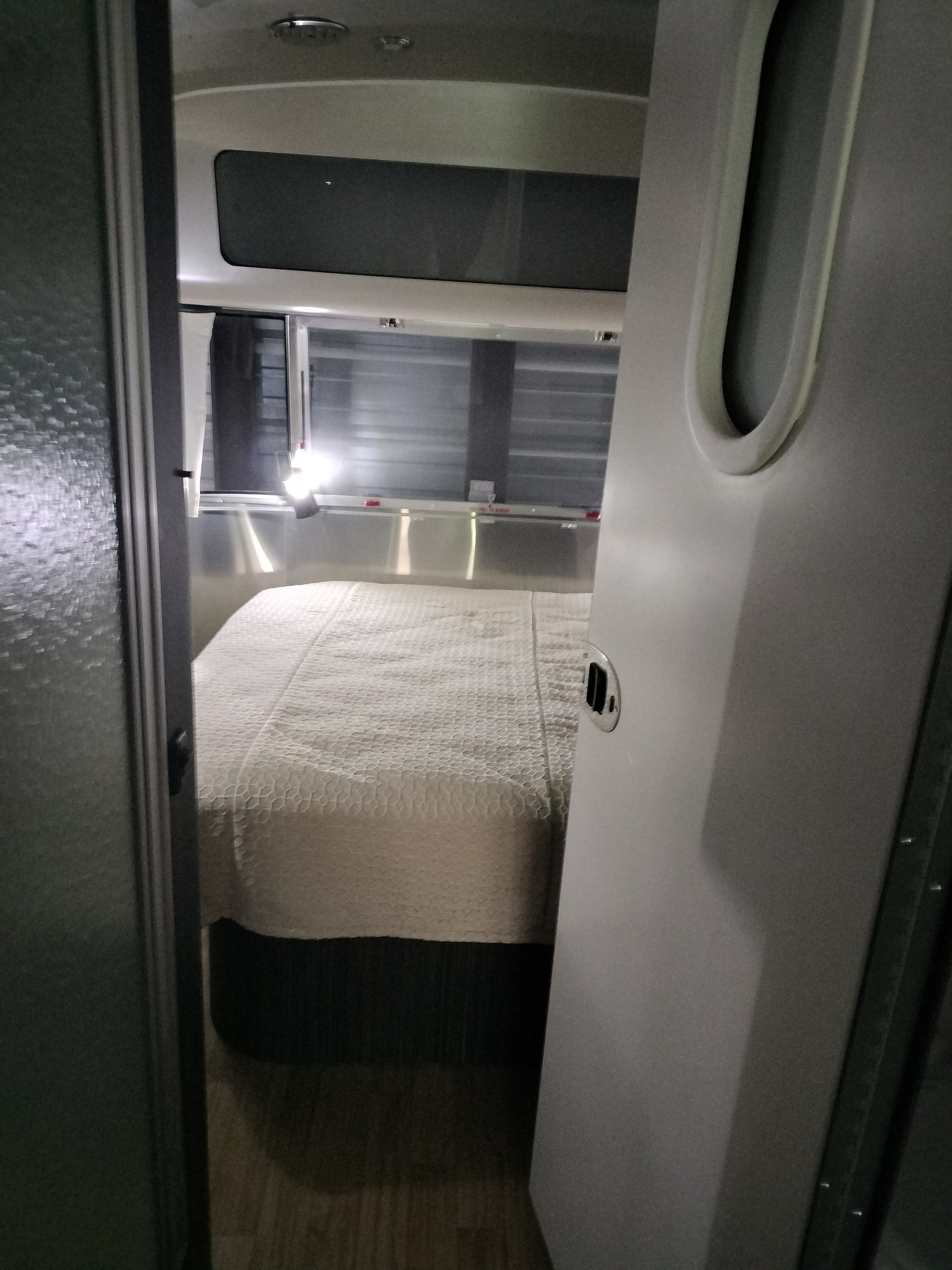 Cozy RV rental interior: bedroom with quilted bed, silver walls, and ample windows.. Airstream International 2019