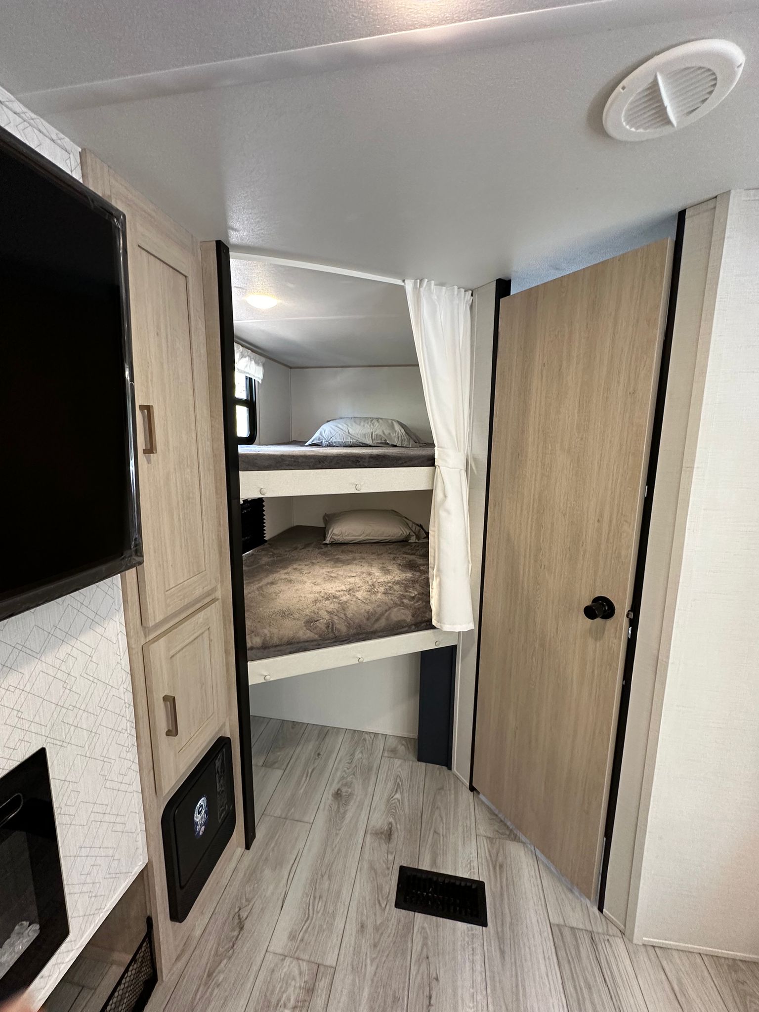 Inside this RV rental, discover a compact sleeping area with two bunk beds, privacy curtains, and a mounted TV.. Avenger ATI 2024