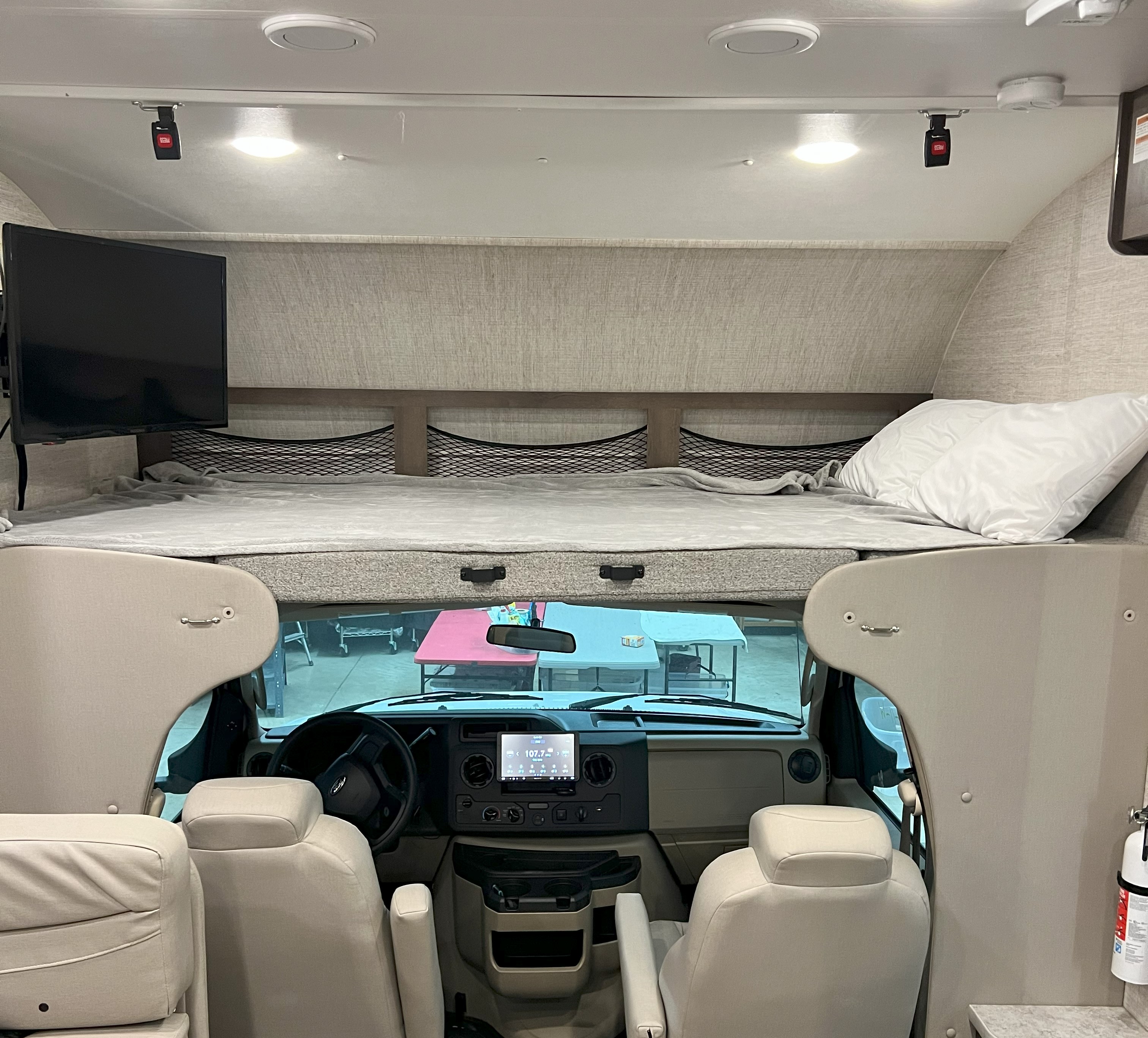 Interior view of an RV rental, showing the overhead bed with TV, plus the full driver's cockpit. Ready for your adventure.. Jayco Redhawk 2022