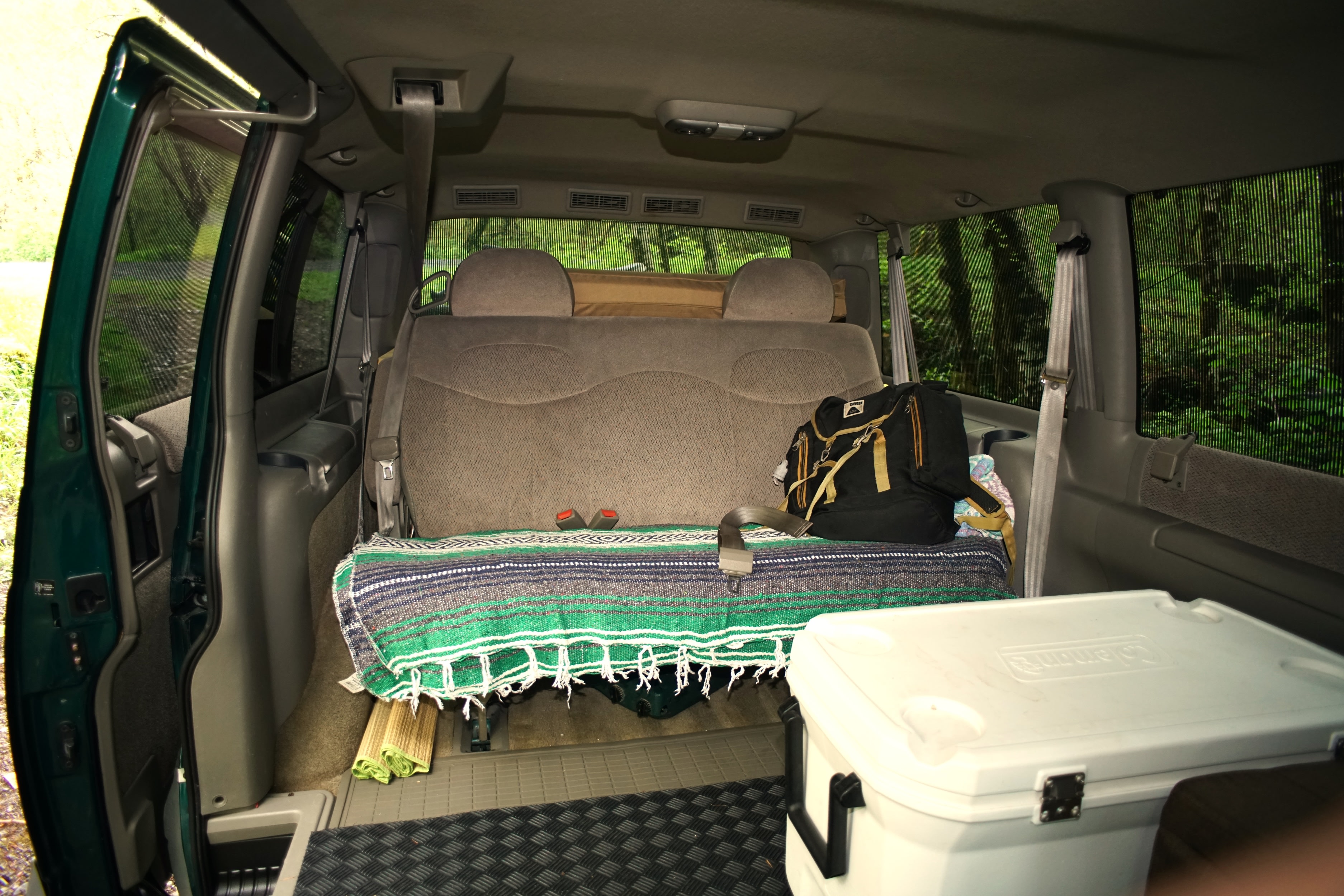 Inside an RV rental: a comfortable van interior with a bed-like seat, cooler, and outdoor gear.. Chevrolet Astro Van AWD 1998