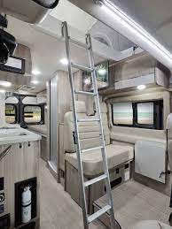 Modern RV rental interior: ladder to bunk, cozy seating, and large windows. Your comfortable road trip adventure awaits.. Thor Sequence 2022