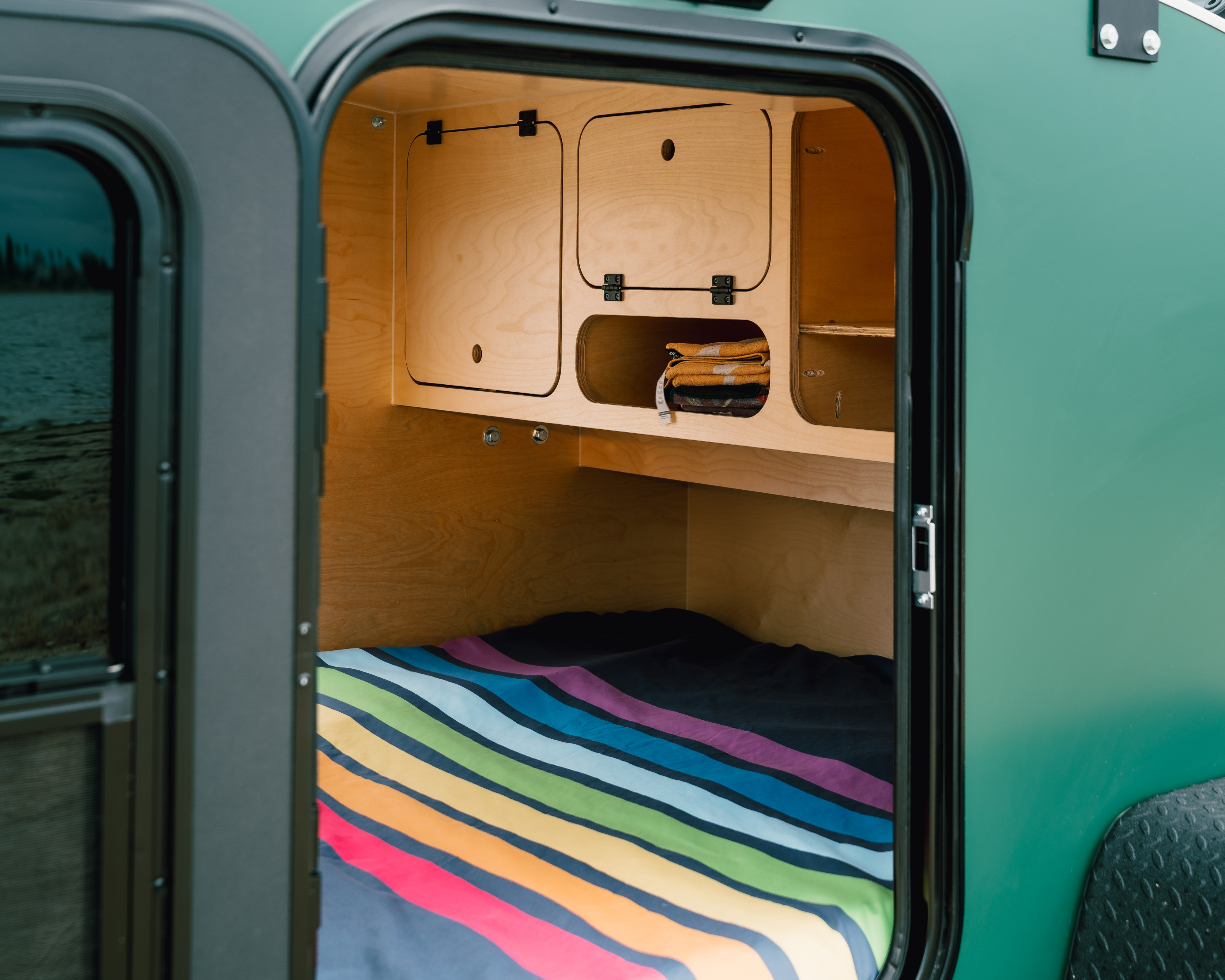 RV rental interior: a cozy sleeping area with a vibrant striped bed, built-in wooden cabinets & storage.. Wander Tears Vaga 2024