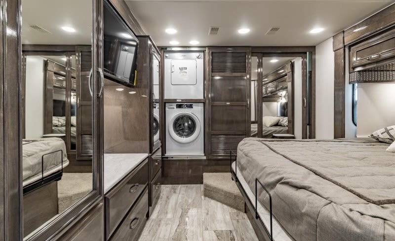 This RV rental's cozy bedroom boasts a stacked washer/dryer, TV, and mirrored closets for a home-like feel.. Entegra Coach Reatta 2022