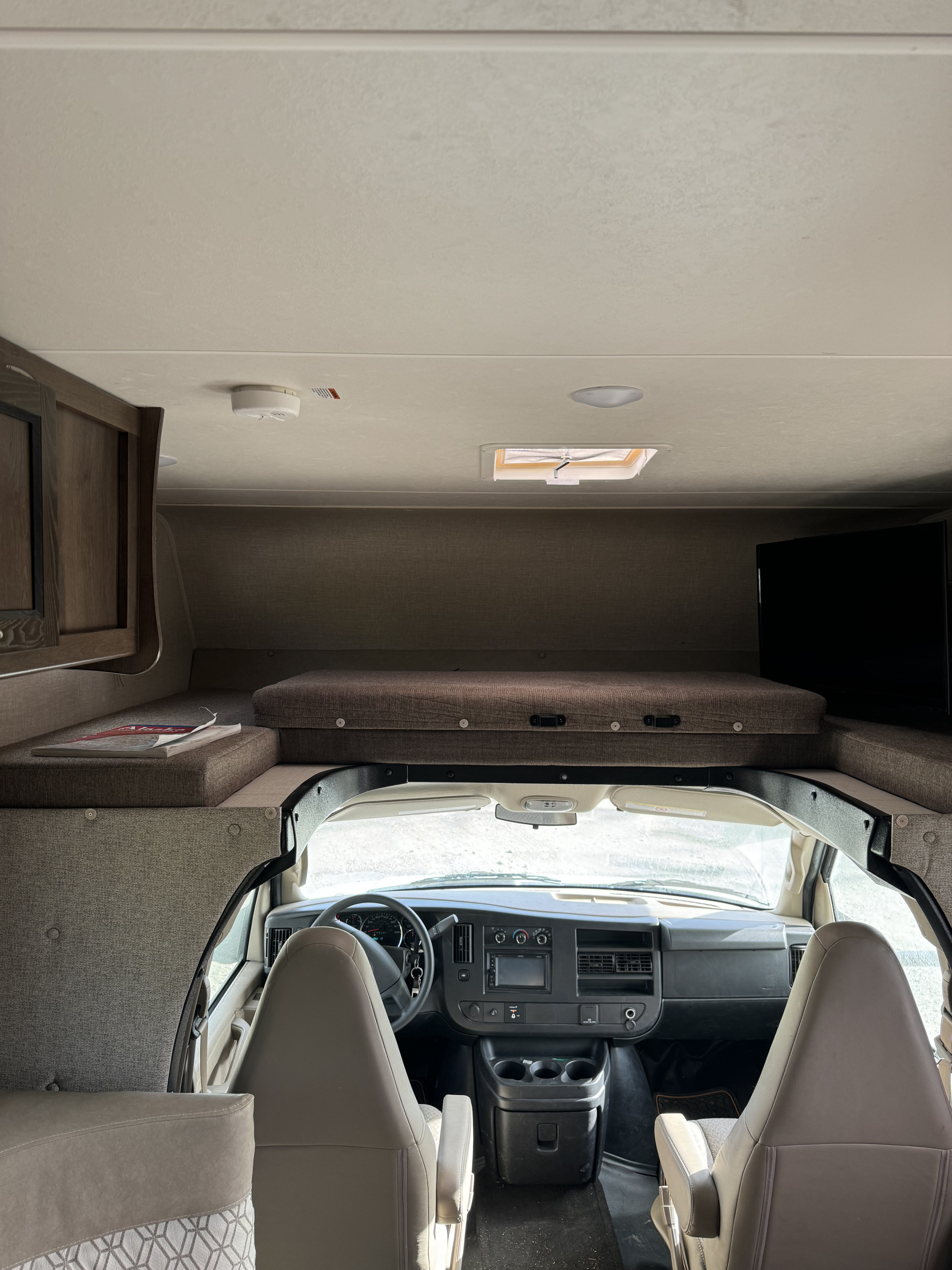 Spacious RV rental interior featuring an over-cab bunk, cockpit area, TV, and ceiling-mounted smoke detector & skylight.. Forest River Coachmen Freelander 2020