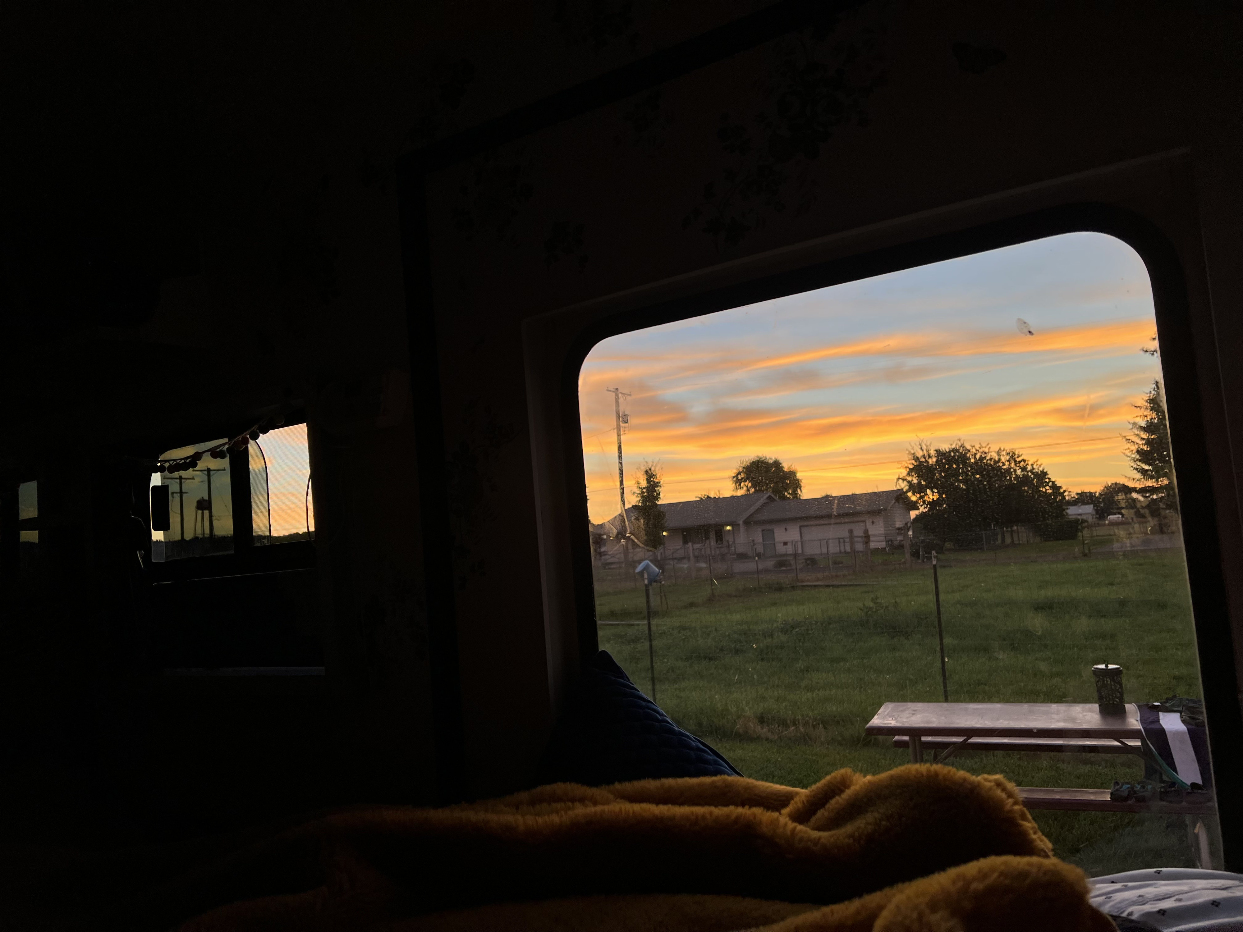 Golden sunset from an RV rental. Cozy interior view of homes, green field, & picnic table outside.. Ford Econoline 1990