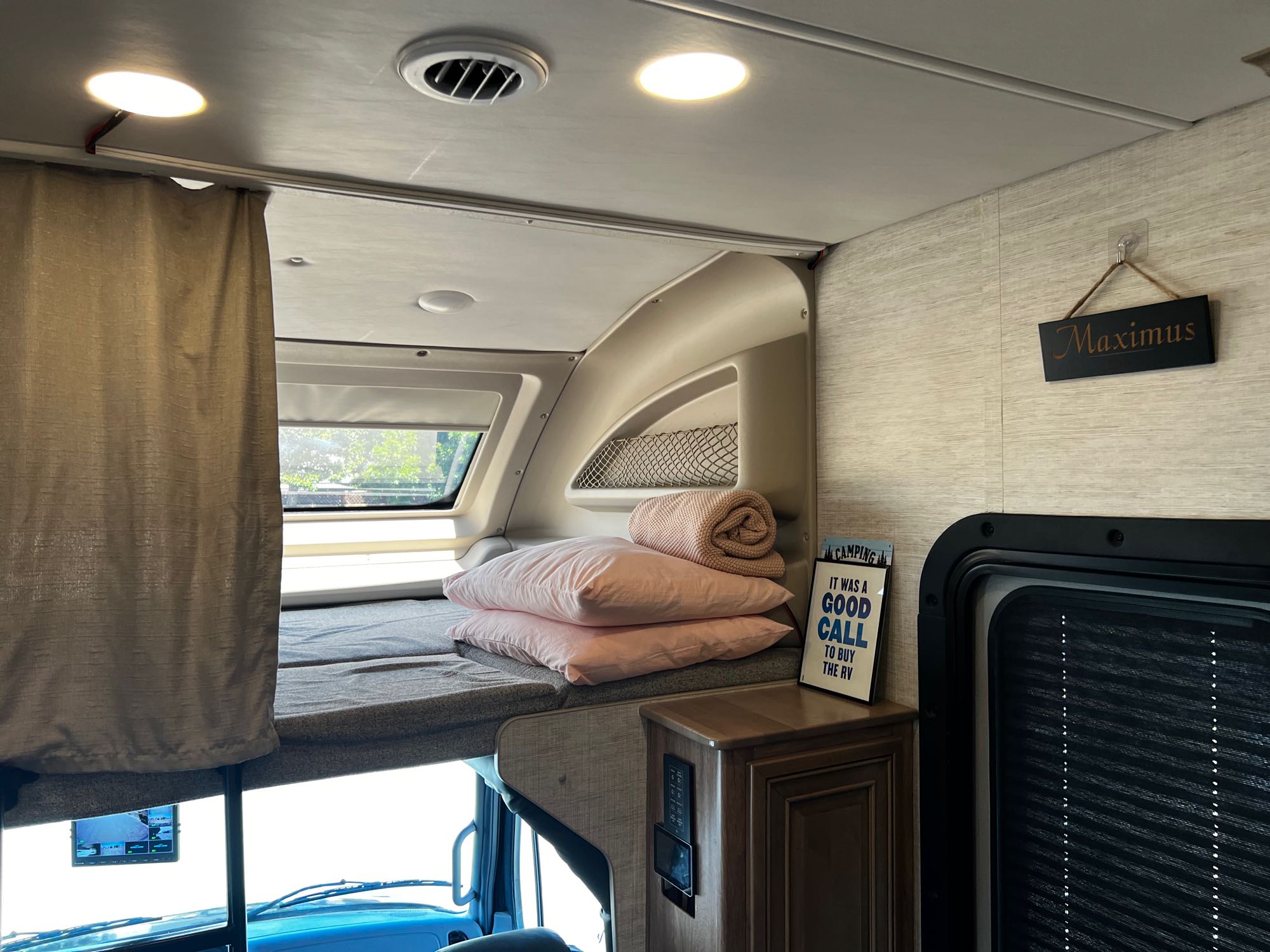 Cozy RV rental bunk bed setup with pink pillows, a privacy curtain, and overhead lights. Ideal for road trip sleeps.. Jayco Seneca 2021
