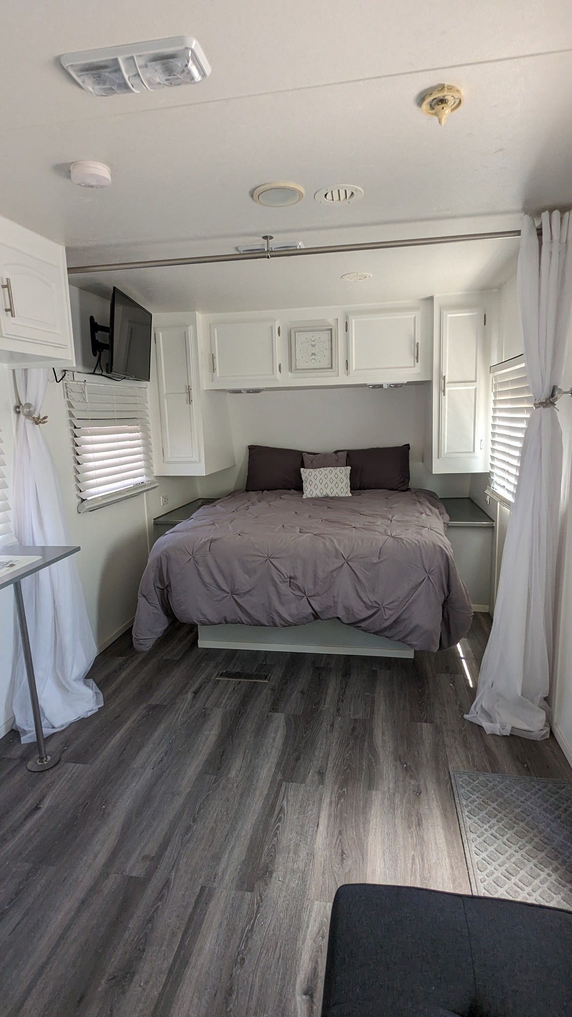 Clean & modern RV rental bedroom featuring a cozy bed, white cabinets, TV, and grey flooring. Perfect for your travels.. Jayco Jay Flight 2011