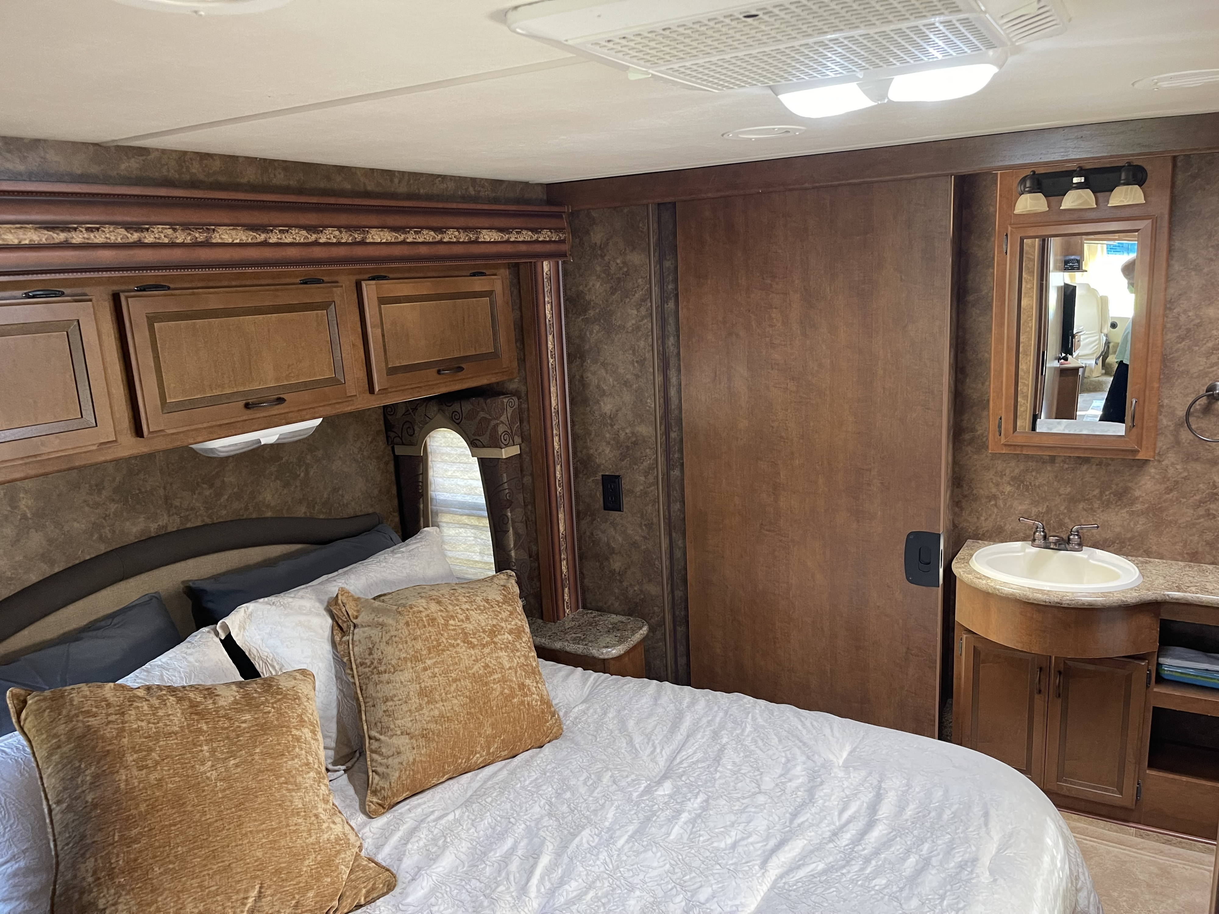 Comfortable RV rental bedroom with a private sink, mirror, and storage cabinets for your travels.. Thor Hurricane 2014