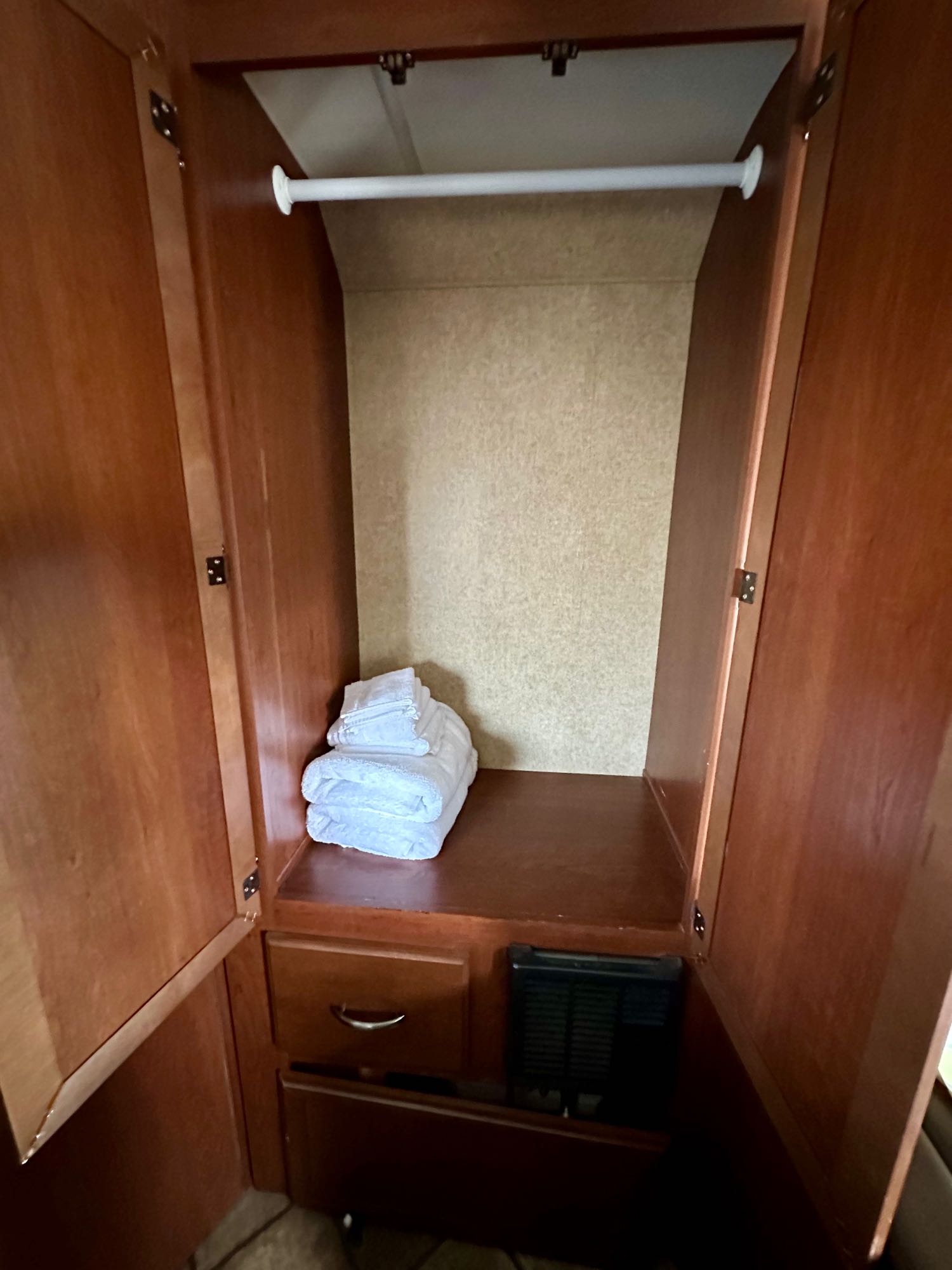 RV rental wardrobe with hanging rod, neatly folded towels, drawer, and utility access below.. Thor Chateau 2014