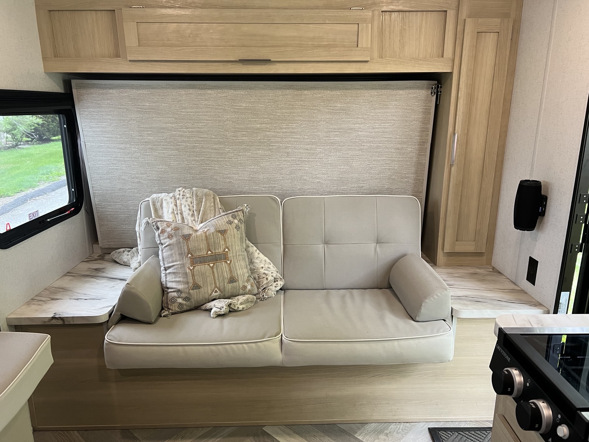 RV rental interior featuring a beige sofa-bed, light wood cabinetry, marble-look counter, and window view.. Forest River Salem FSX 2023