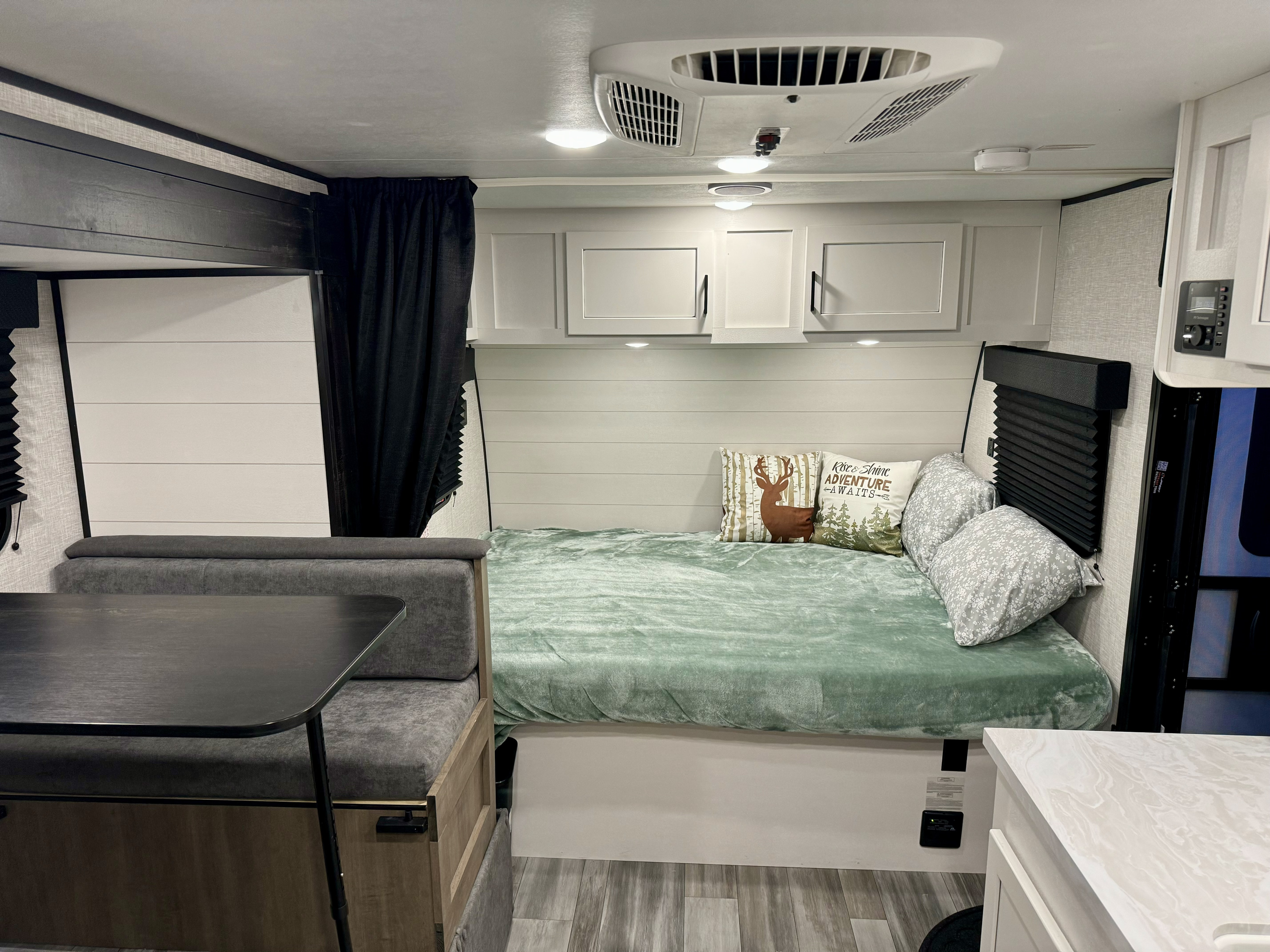 Modern RV rental interior with cozy bed, dinette, white cabinets, and wood-look flooring. Ready for adventure!. Jayco Jay Flight SLX 2024