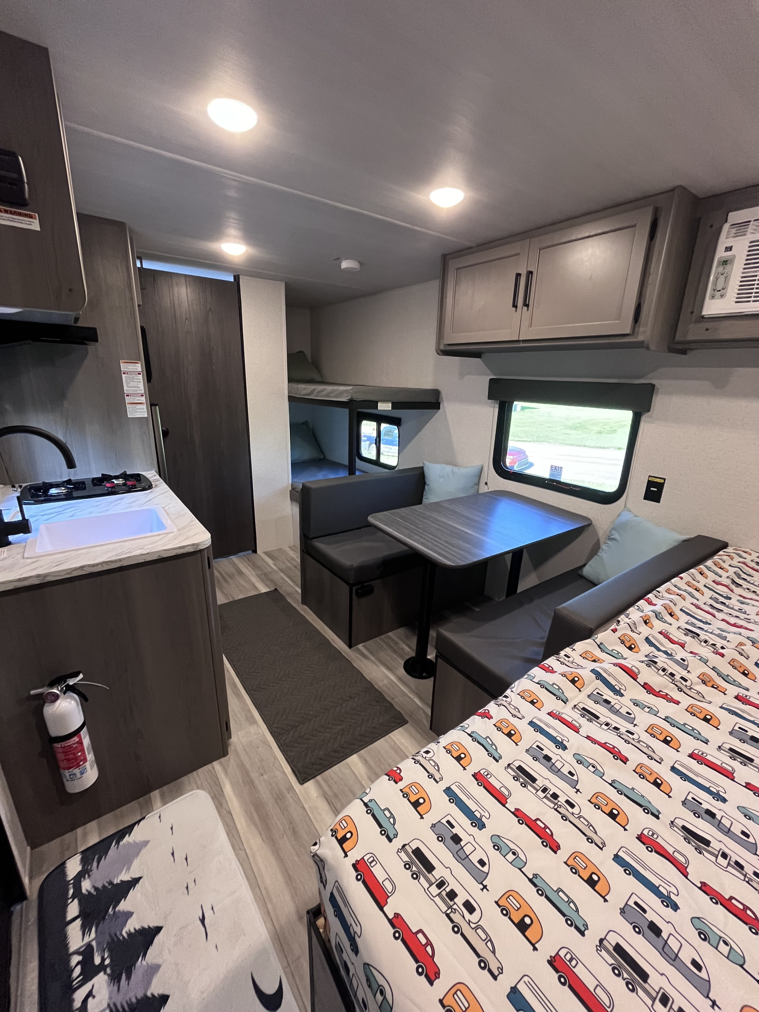 Inside an RV rental: kitchen, dinette, bunk beds, & cozy sleeping area with car-themed bedding. Ready for your adventure.. Keystone RV Hideout Sport 2024