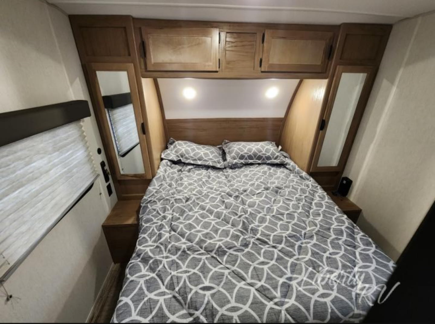 RV rental master bedroom featuring a comfortable bed, overhead cabinets, and built-in nightstands.. Forest River Cherokee Grey Wolf 29NM 2024