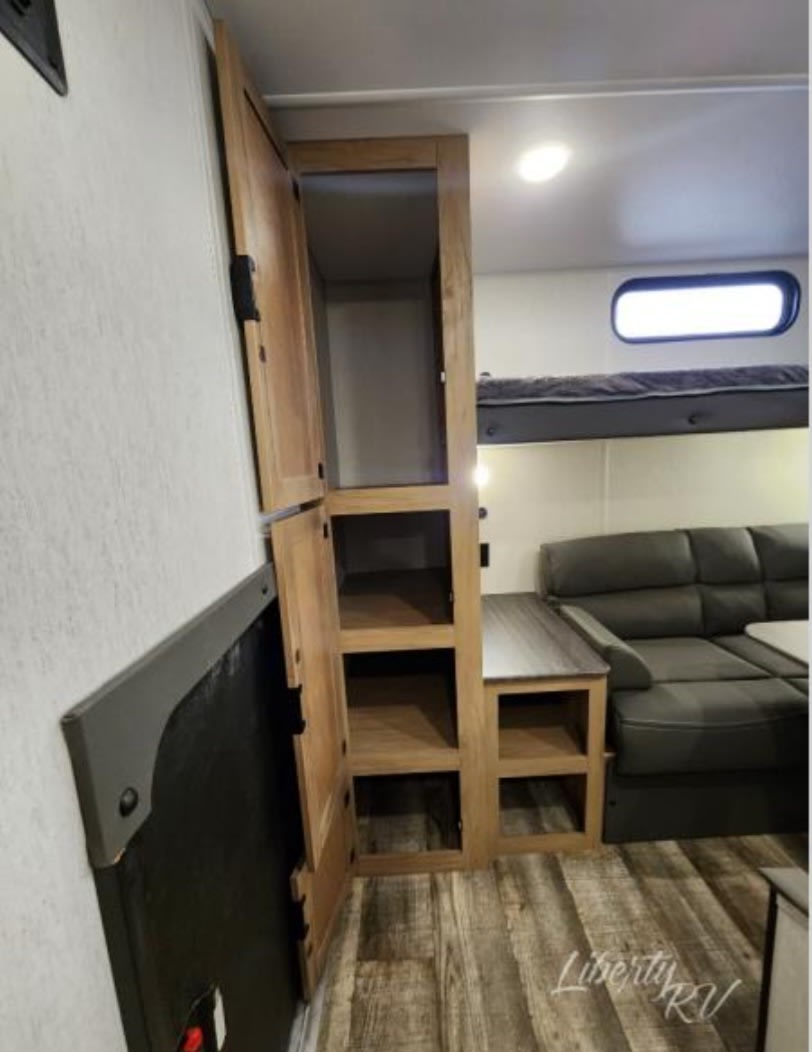 RV rental bunkhouse interior features cozy L-sofa, upper bunk bed, and clever storage solutions.. Forest River Cherokee Grey Wolf 29NM 2024