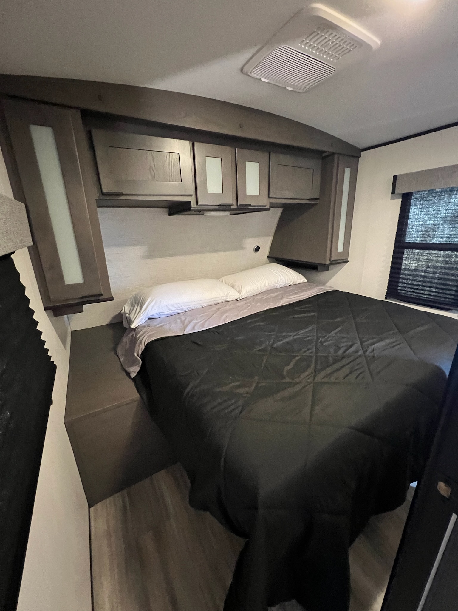RV rental bedroom interior: a cozy bed with dark bedding, overhead cabinets, and window blinds for comfortable travel.. Cruiser RV MPG Ultra Lite 2021